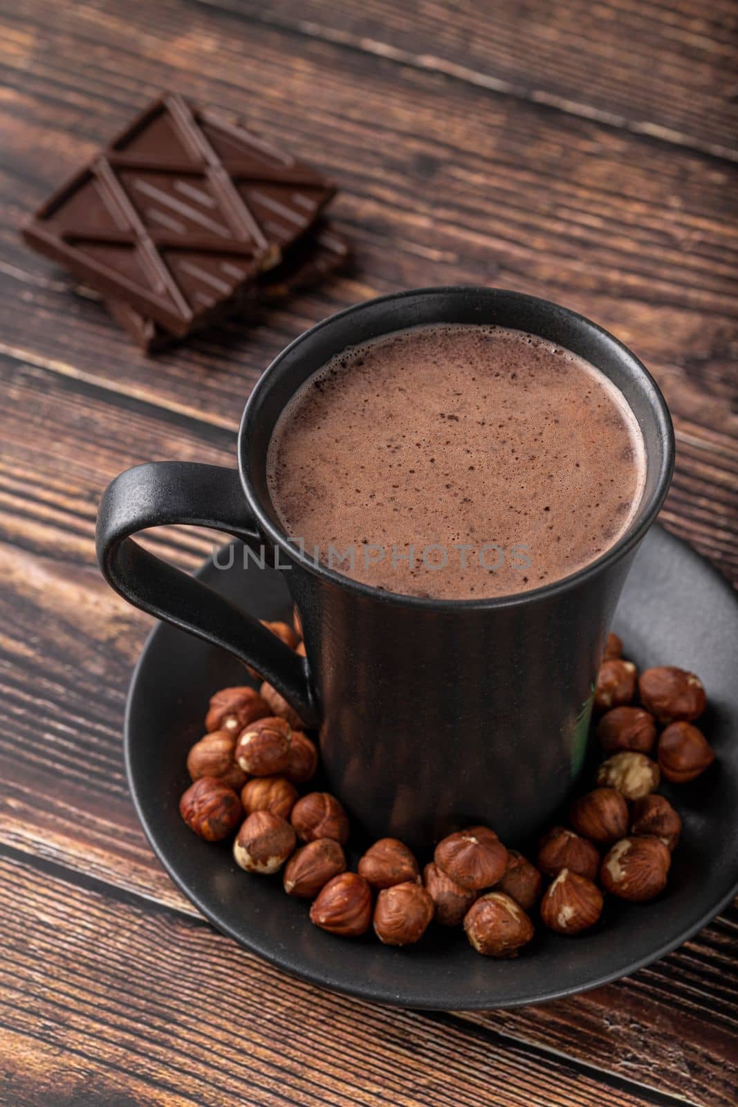 Hazelnut hot chocolate with chocolate next to it on wooden table