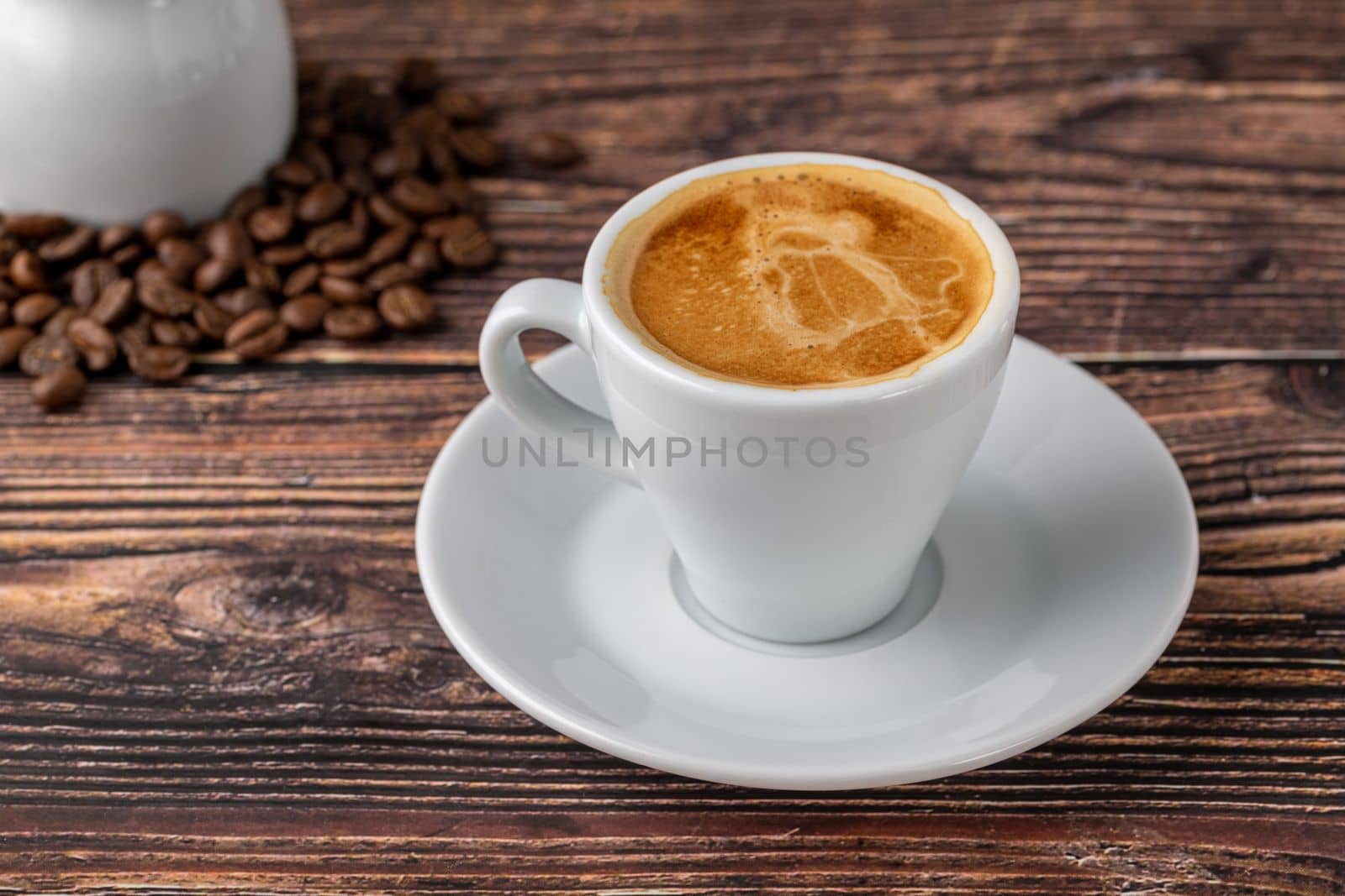 Espresso in white cup with milk next to it on wooden table