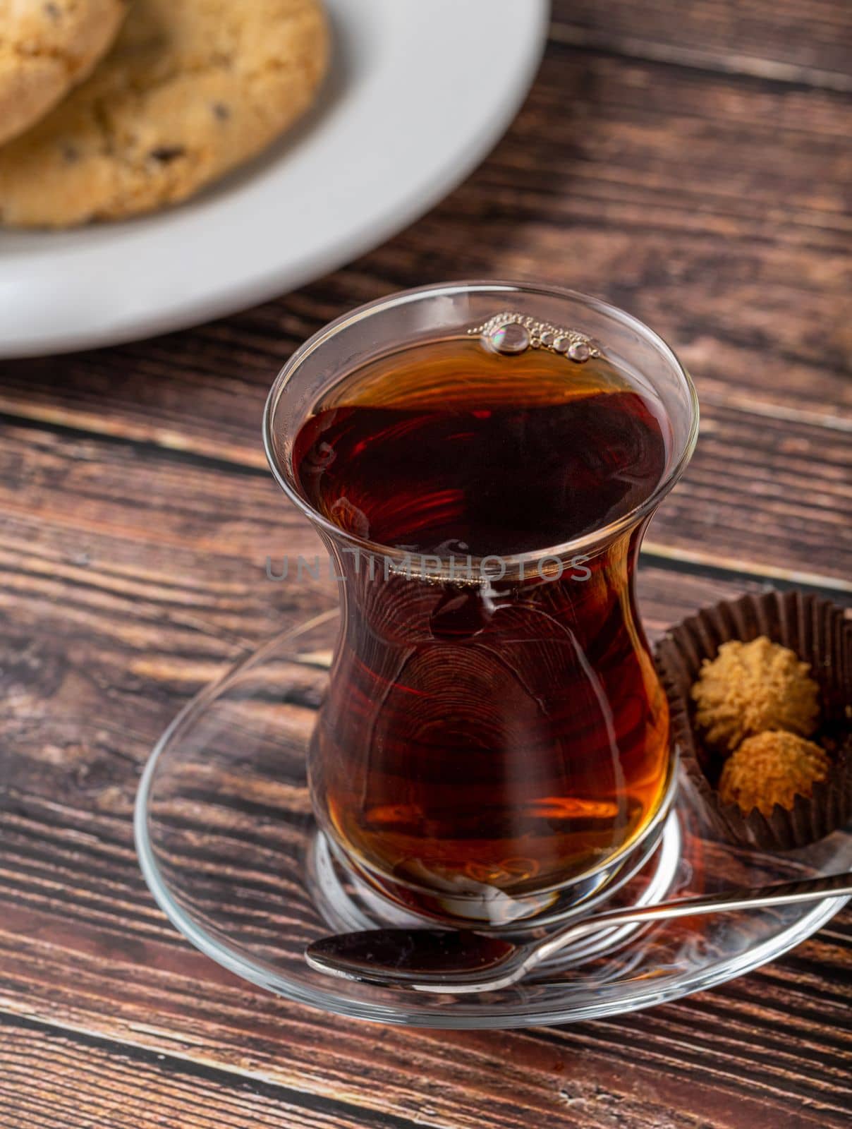 Freshly brewed black Turkish tea with cookies on wooden table by Sonat