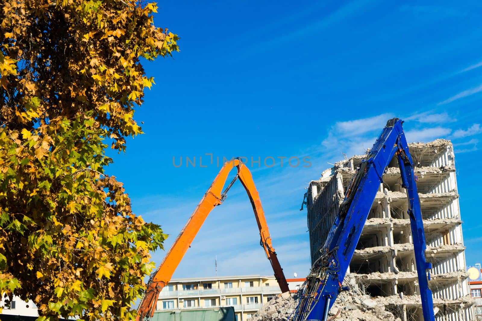 Demolition of a old building with sloopkraan against blue clouds sky.