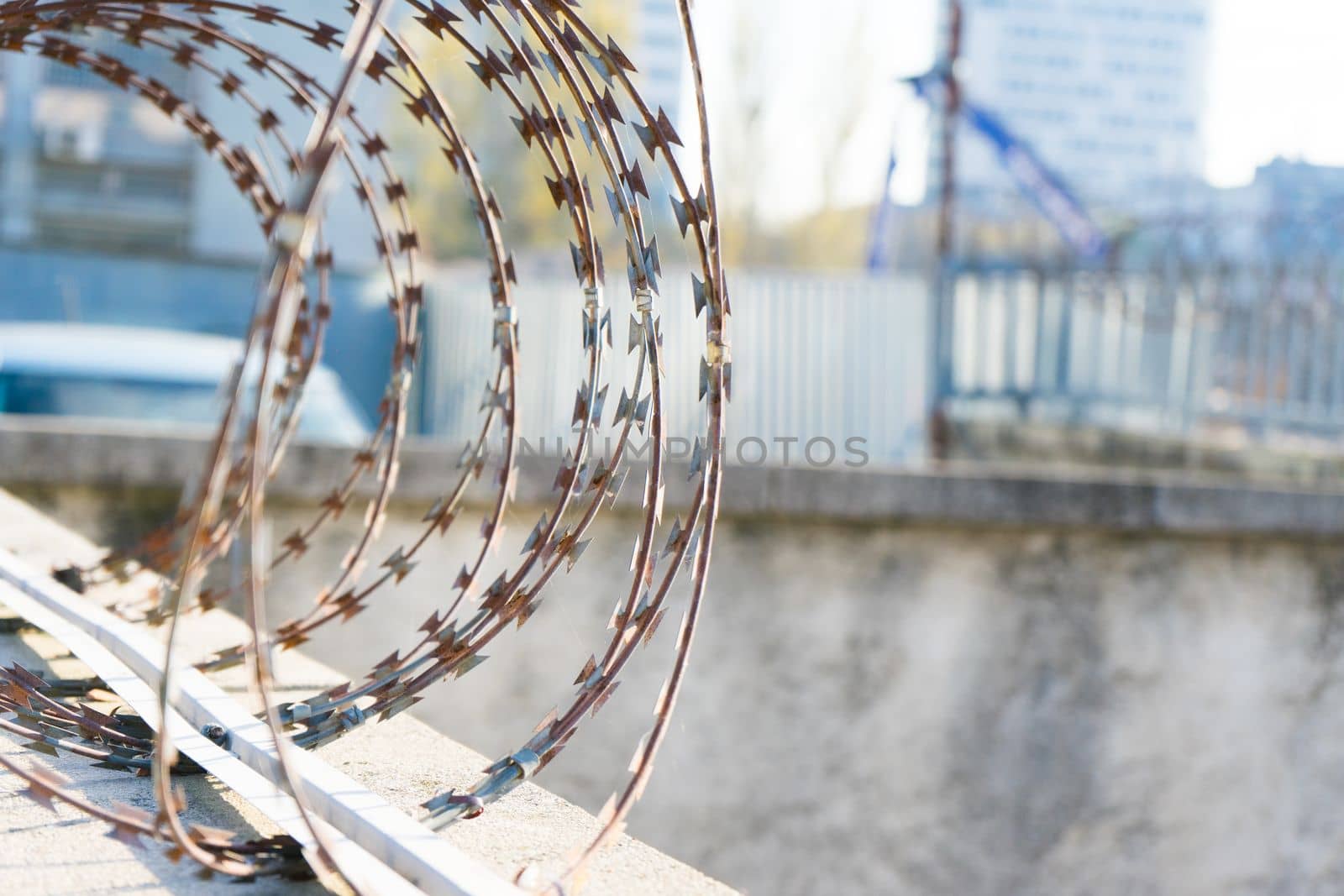 Barbered wire over blue sky and on building ground, rusty