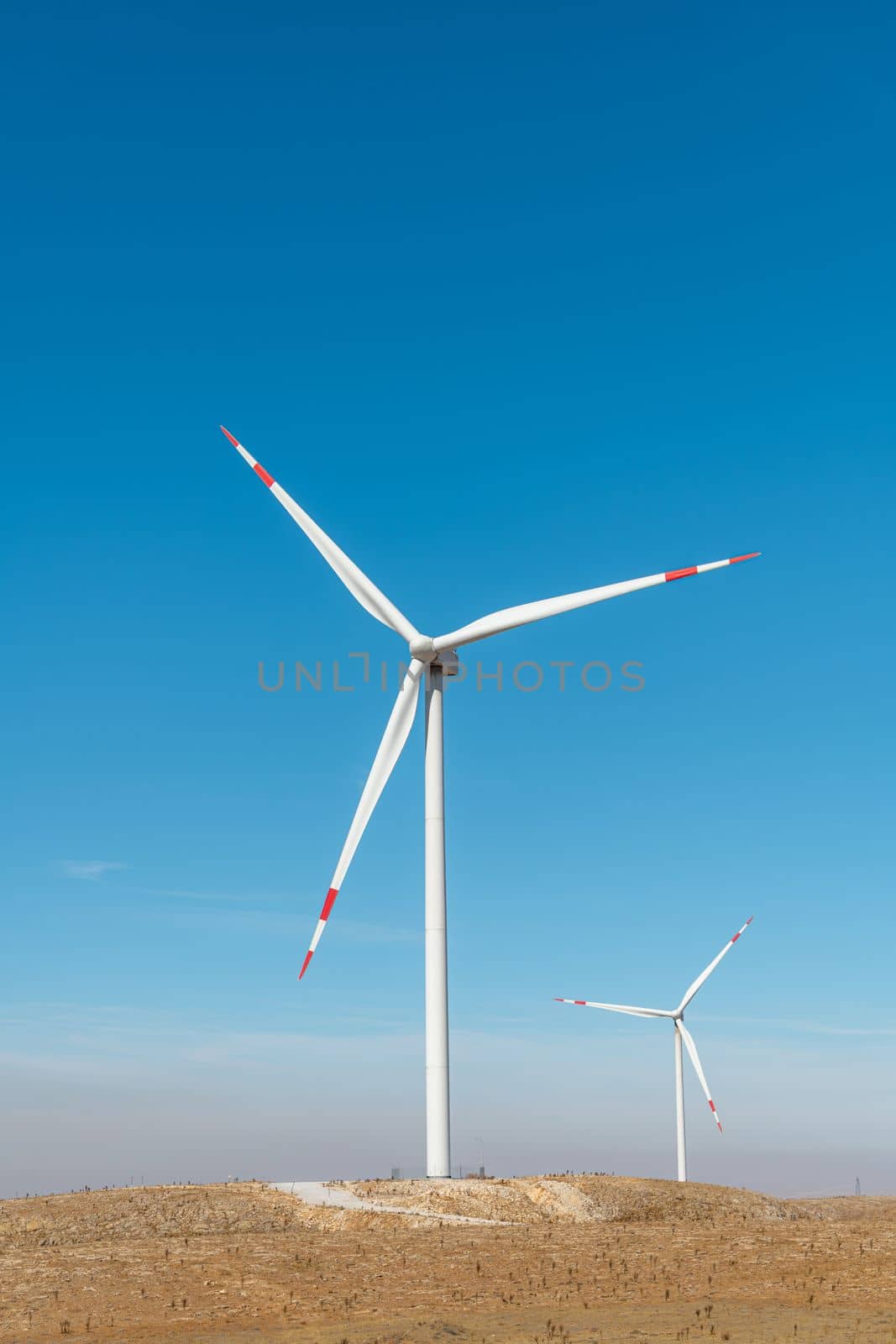 Multiple wind turbines standing on a hill at sunrise and generating electricity