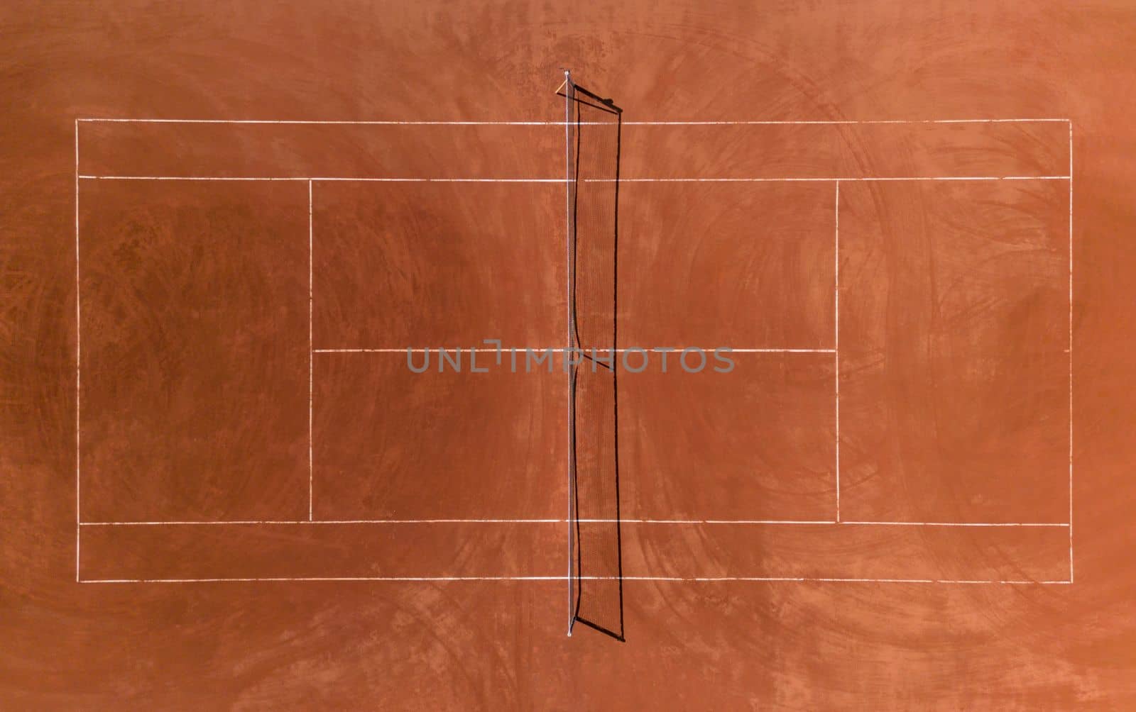 Aerial view of empty clay tennis court on a sunny day