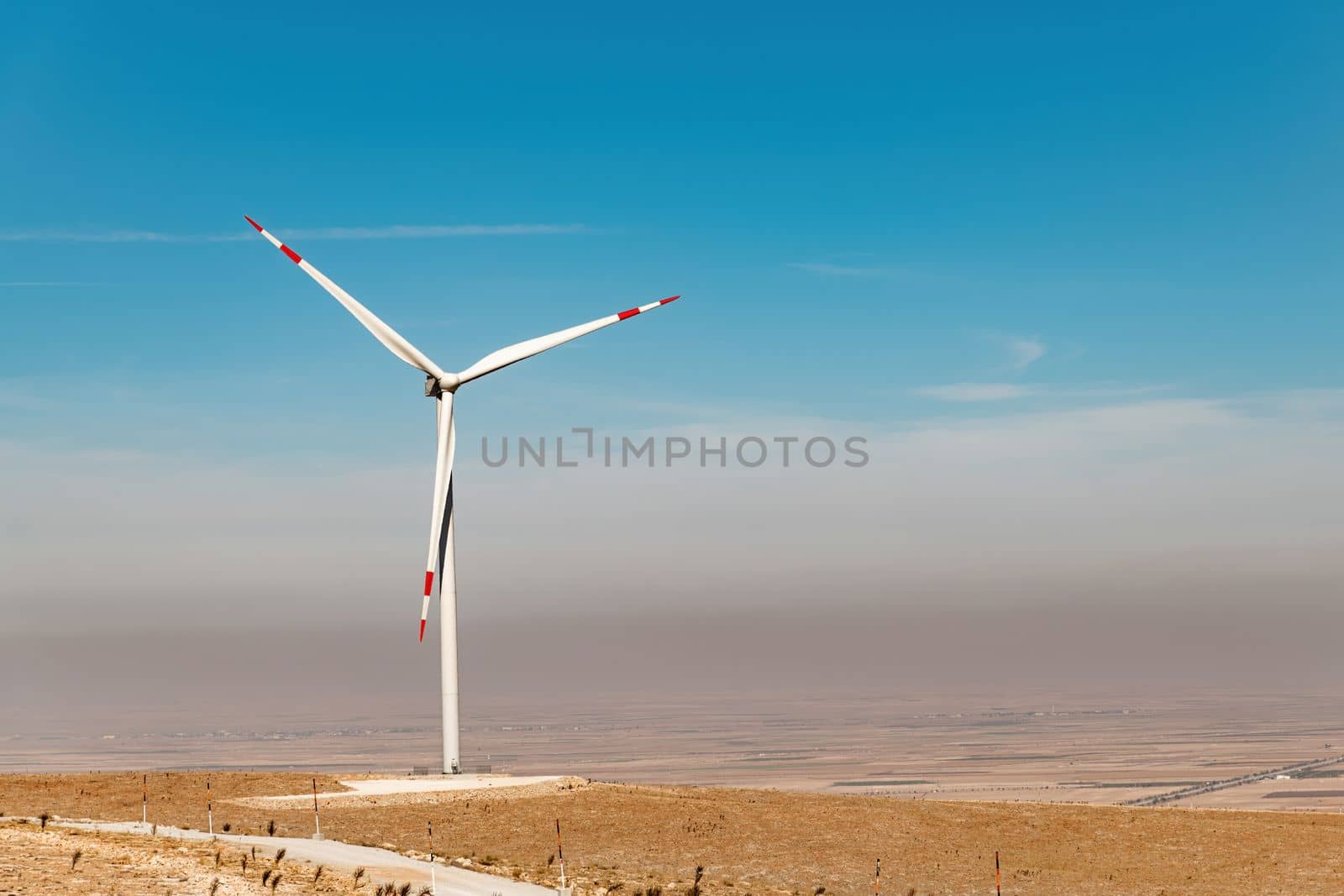 Wind turbine standing on a hill and generating electricity at sunrise