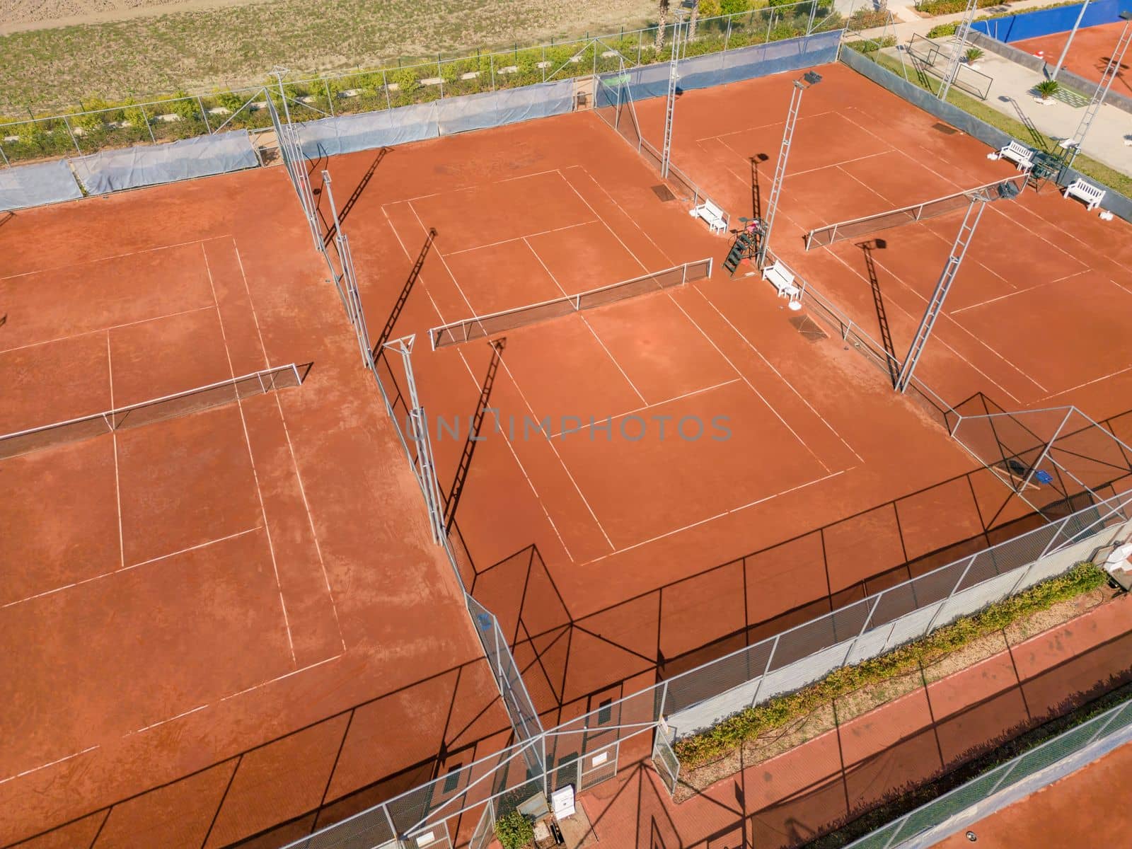 Aerial view of empty clay tennis court on a sunny day by Sonat