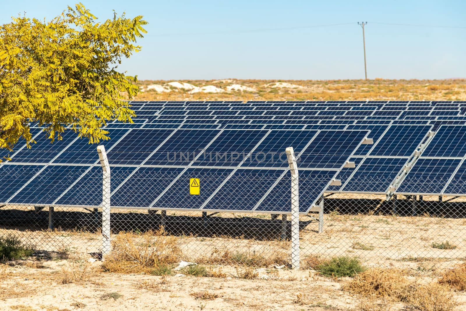 Solar field with fenced solar panels at sunset