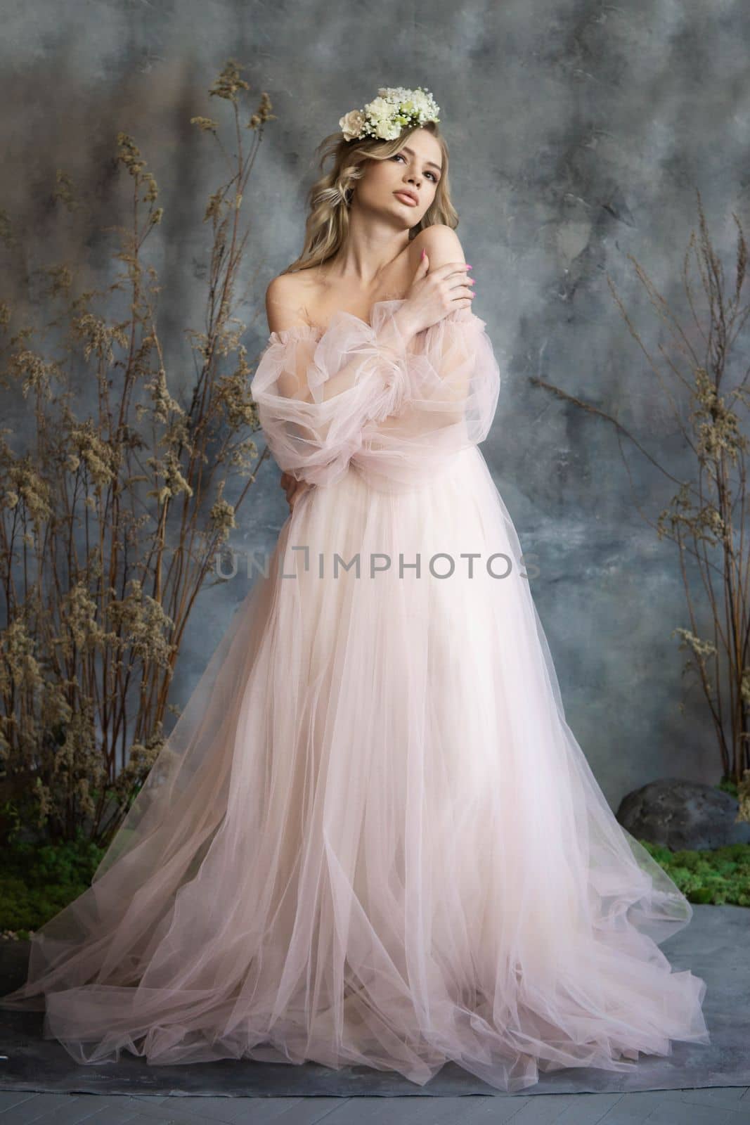 A young blonde in an airy tulle pink dress. Spring portrait of a woman