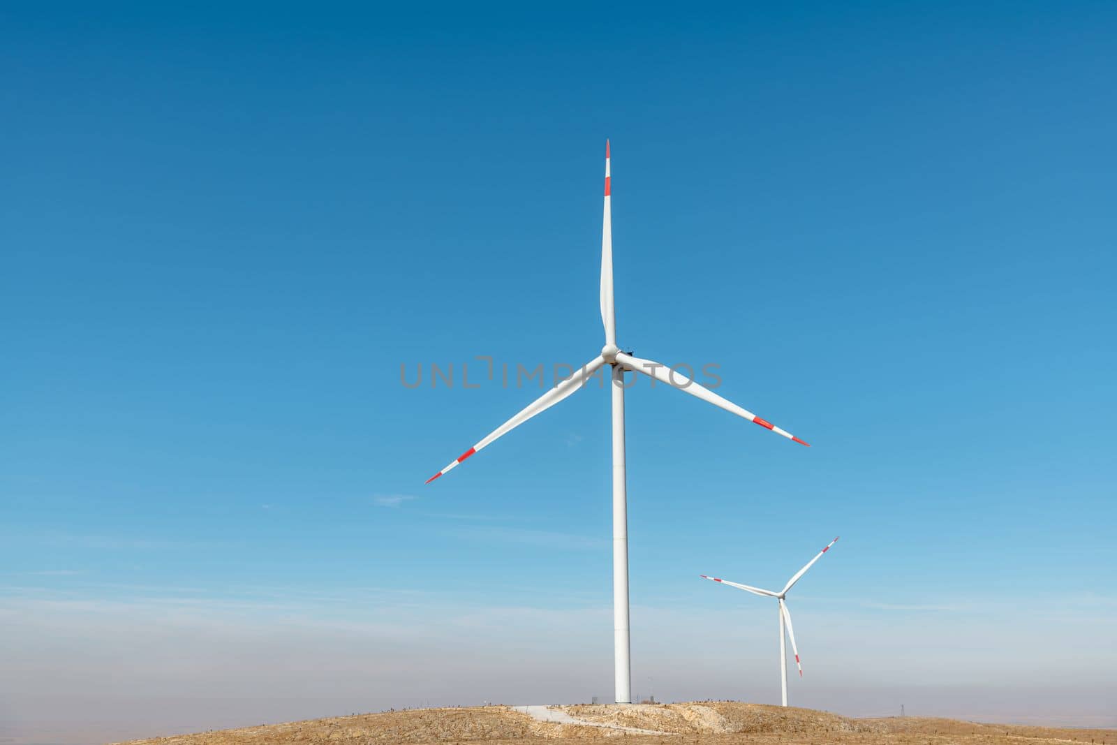 Multiple wind turbines standing on a hill at sunrise and generating electricity