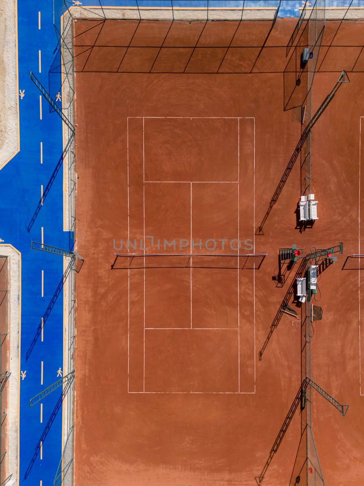 Aerial view of empty clay tennis court on a sunny day