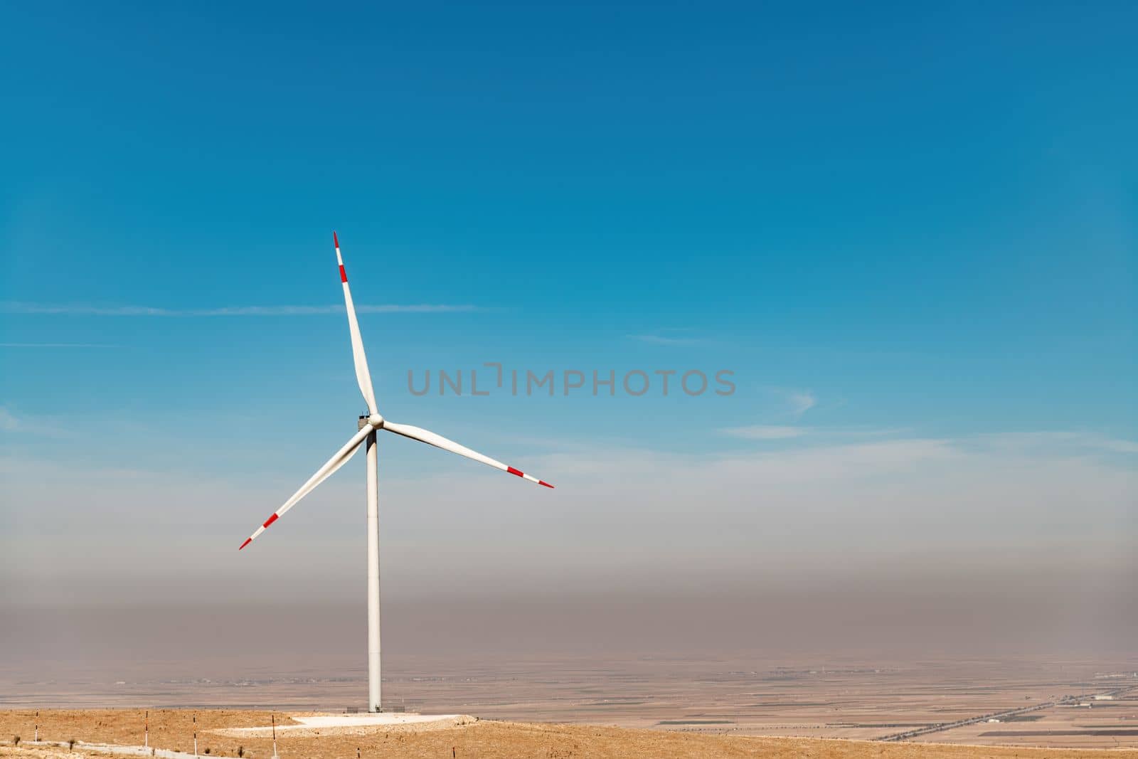 Wind turbine standing on a hill and generating electricity at sunrise