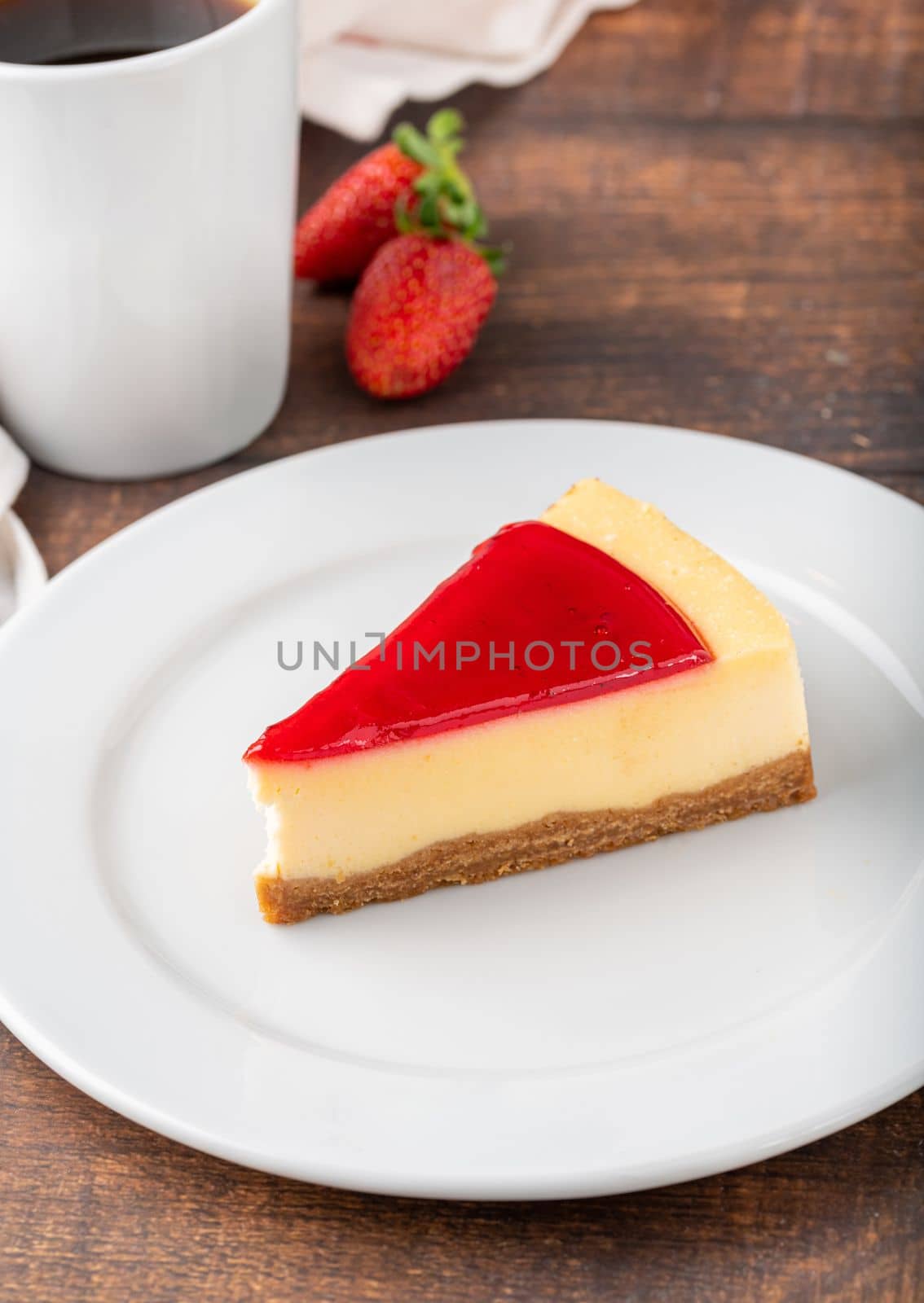 Delicious strawberry cheesecake with coffee next to it on wooden table by Sonat