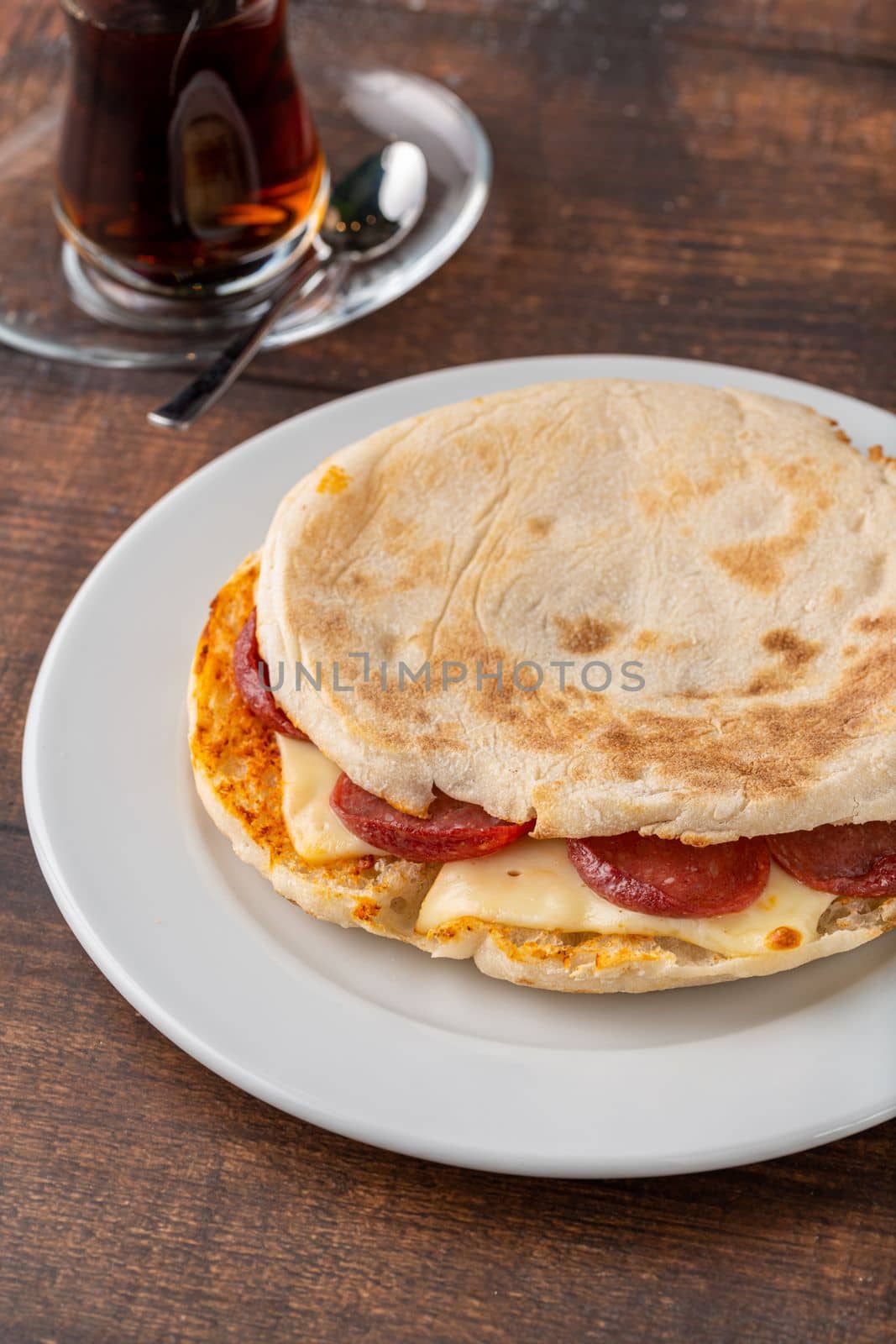 Flatbread toast with salami, turkish sausage and cheddar on a dark stone table by Sonat