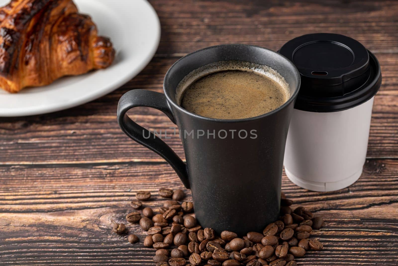 Relaxing americano coffee in black porcelain cup and take away cup on wooden table