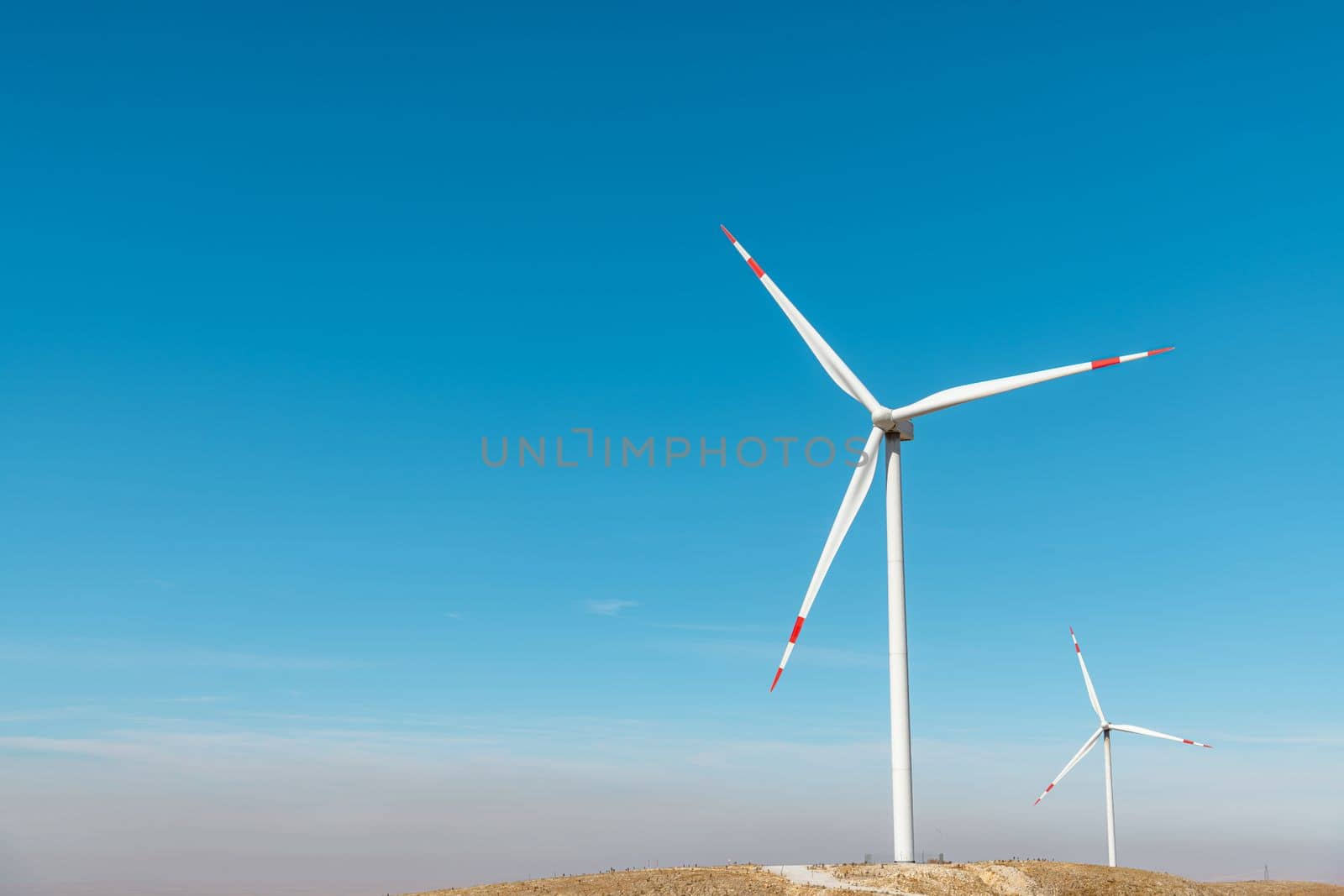 Multiple wind turbines standing on a hill at sunrise and generating electricity