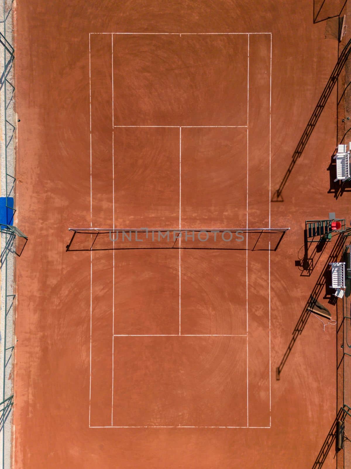 Aerial view of empty clay tennis court on a sunny day by Sonat