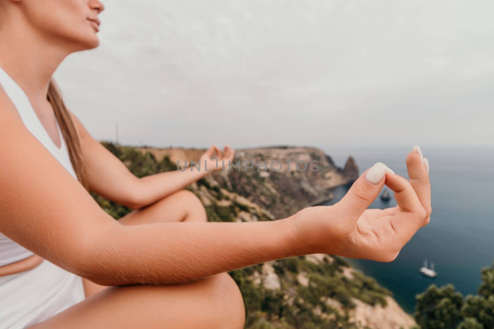 Middle aged well looking woman with black hair doing Pilates with the ring on the yoga mat near the sea on the pebble beach. Female fitness yoga concept. Healthy lifestyle, harmony and meditation.