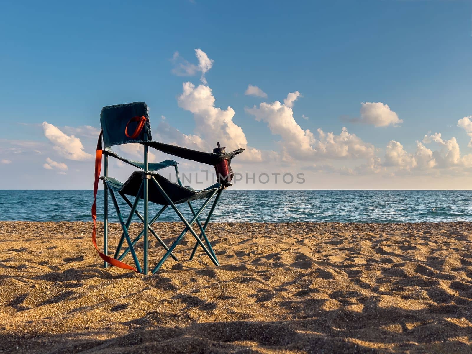 Folding camping chair facing the sea on the beach in the evening in autumn by Sonat