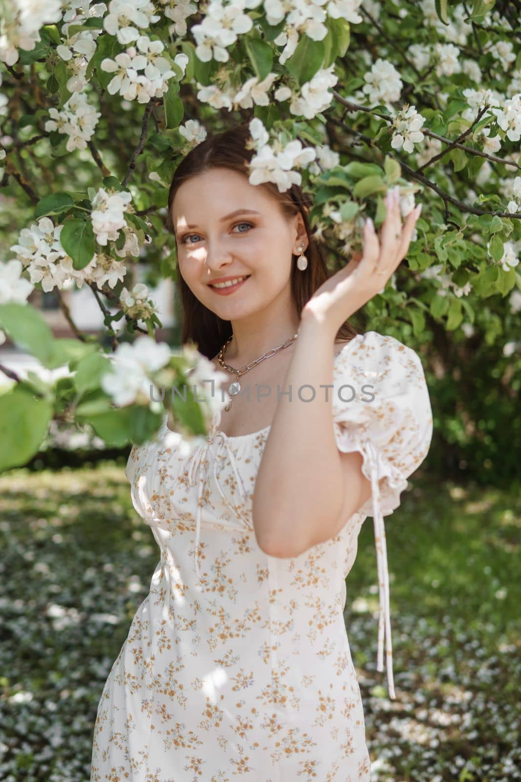 An attractive long-haired woman walks in the spring in the park of blooming apple trees. by Annu1tochka