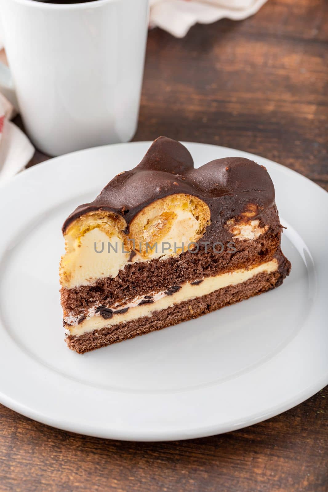 Cake with profiteroles on a white porcelain plate with filter coffee on the side