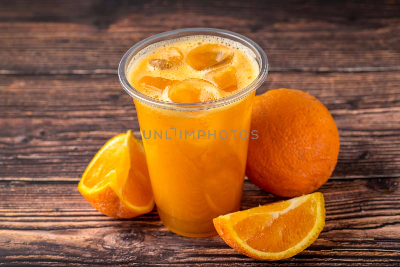 Freshly squeezed orange juice with ice cubes on wooden table