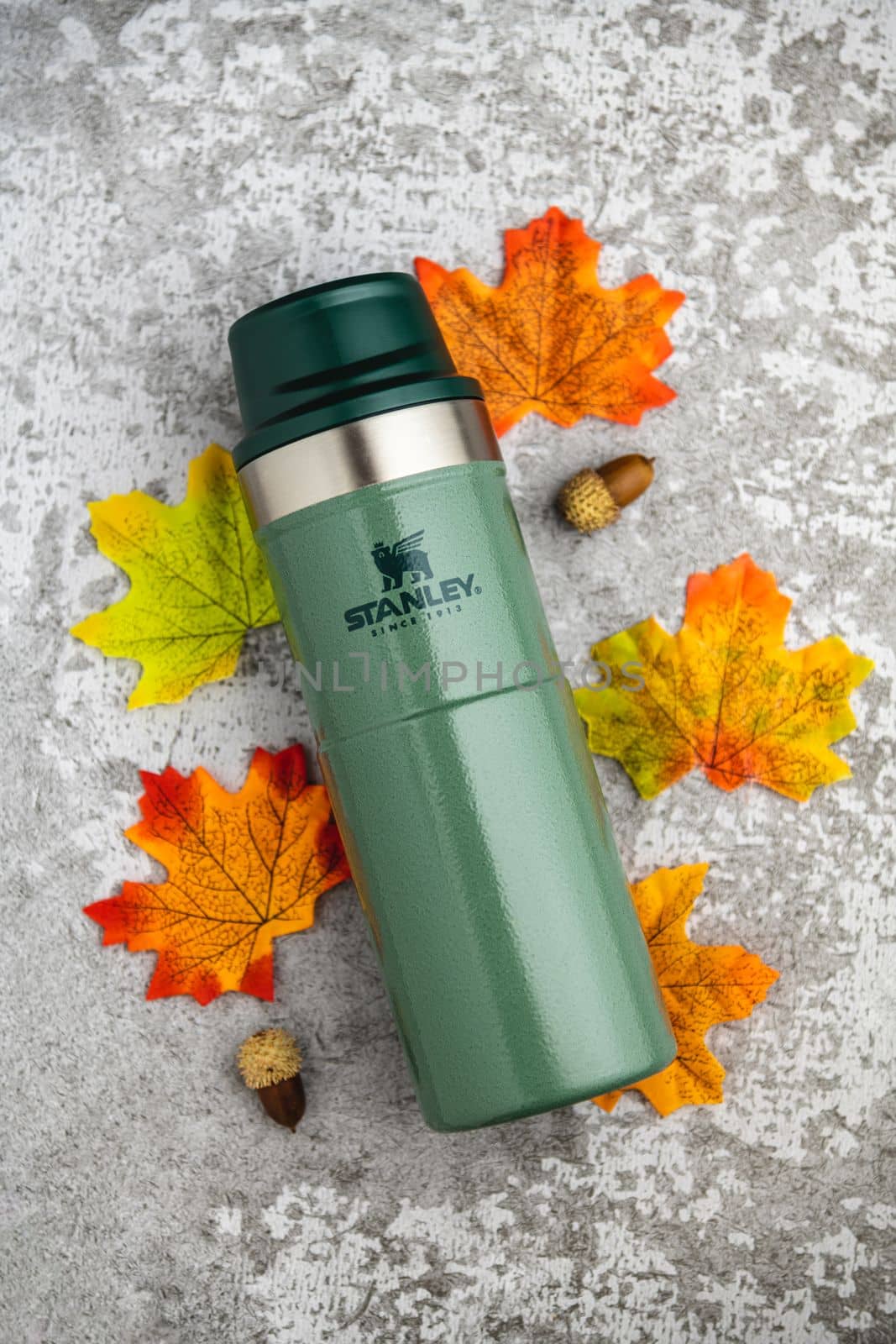 Antalya, Turkey - November 28, 2022: Stanley Action Trigger thermos mug with leaves in autumn colors on stone background by Sonat