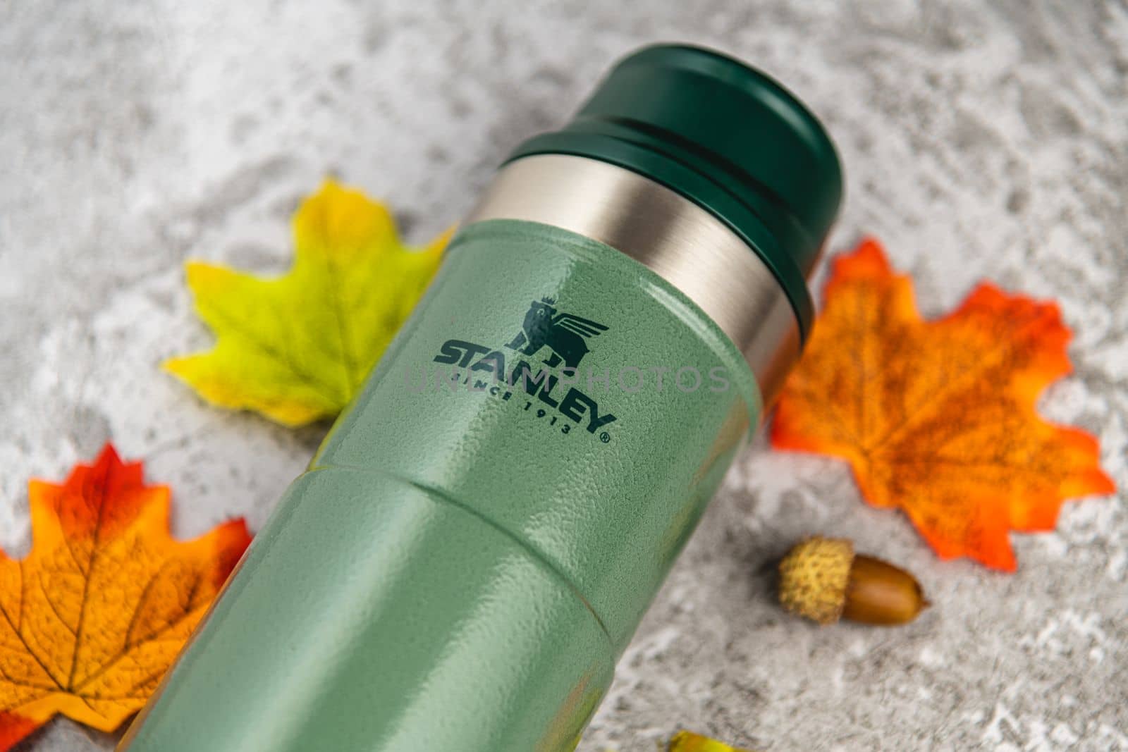 Antalya, Turkey - November 28, 2022: Stanley Action Trigger thermos mug with leaves in autumn colors on stone background