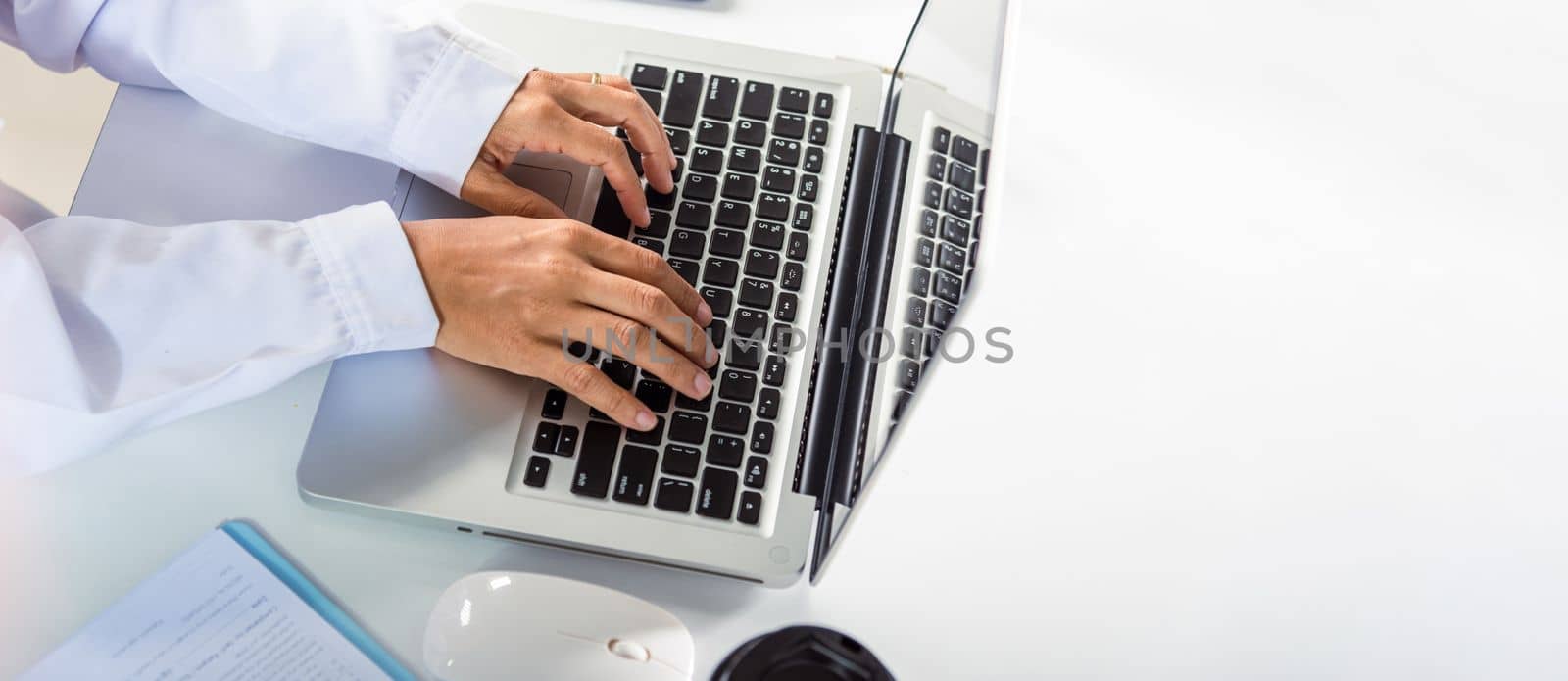 Hands of female doctor wear uniform in hospital she typing information on keyboard laptop by Sorapop