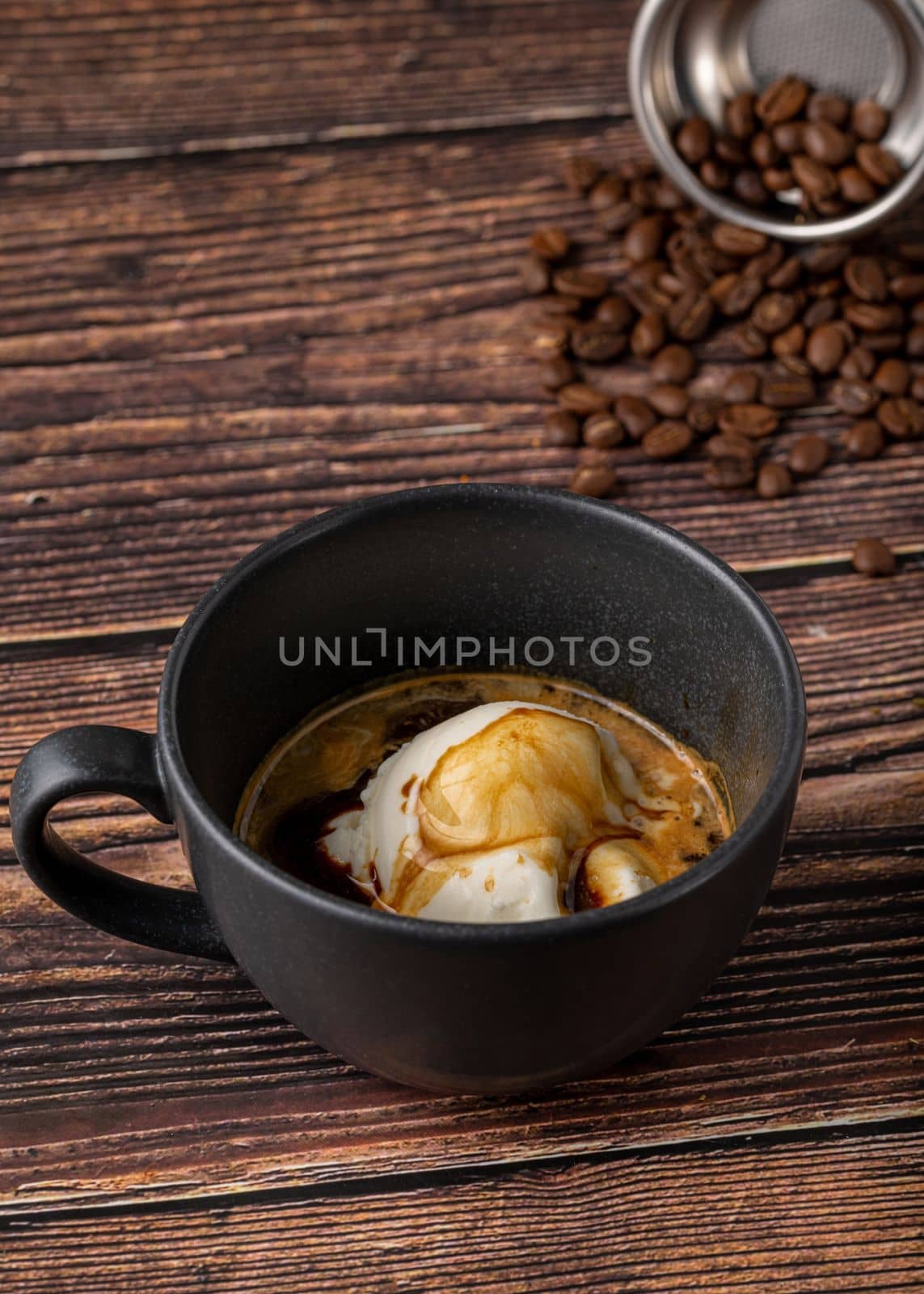 Espresso with ice cream in black porcelain cup on wooden table. Affogato Coffee by Sonat