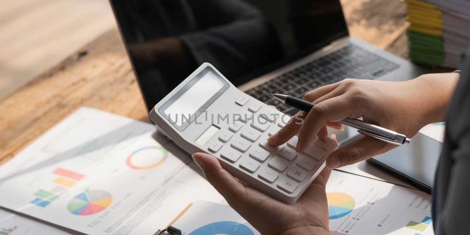 Business woman using calculator to calculate financial report, working at office with laptop computer on table. Asian female accountant or banker making calculations. finances and economy concept..