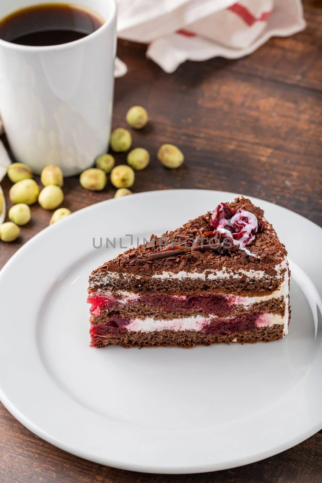 Cherry cake on white porcelain plate on wooden table