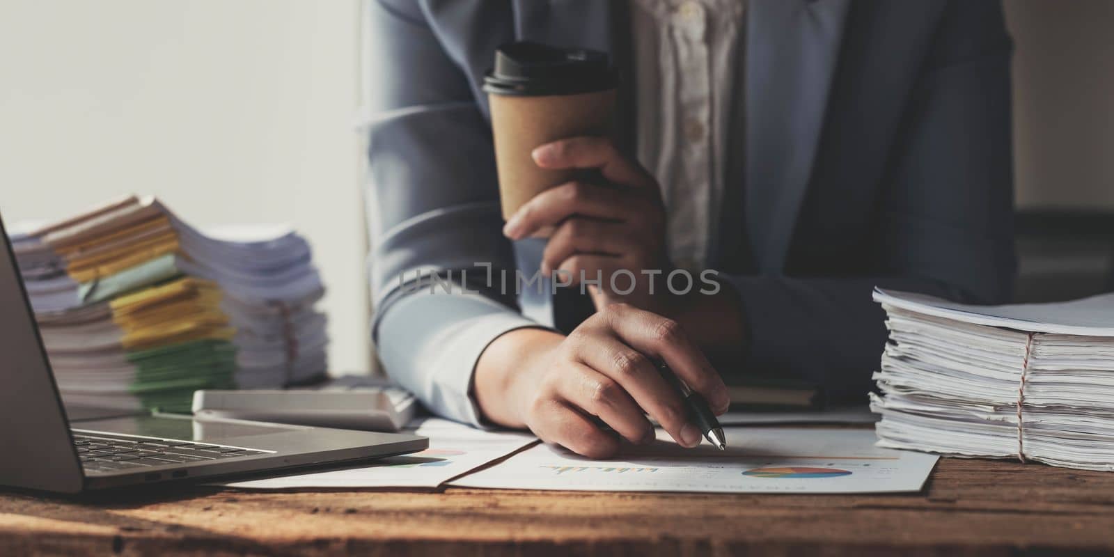 Annual, summary report, laptop and paper placed at office desk. Person back view of Asian woman work online and plan financial data with laptop, work from home. Business woman and planner concept..