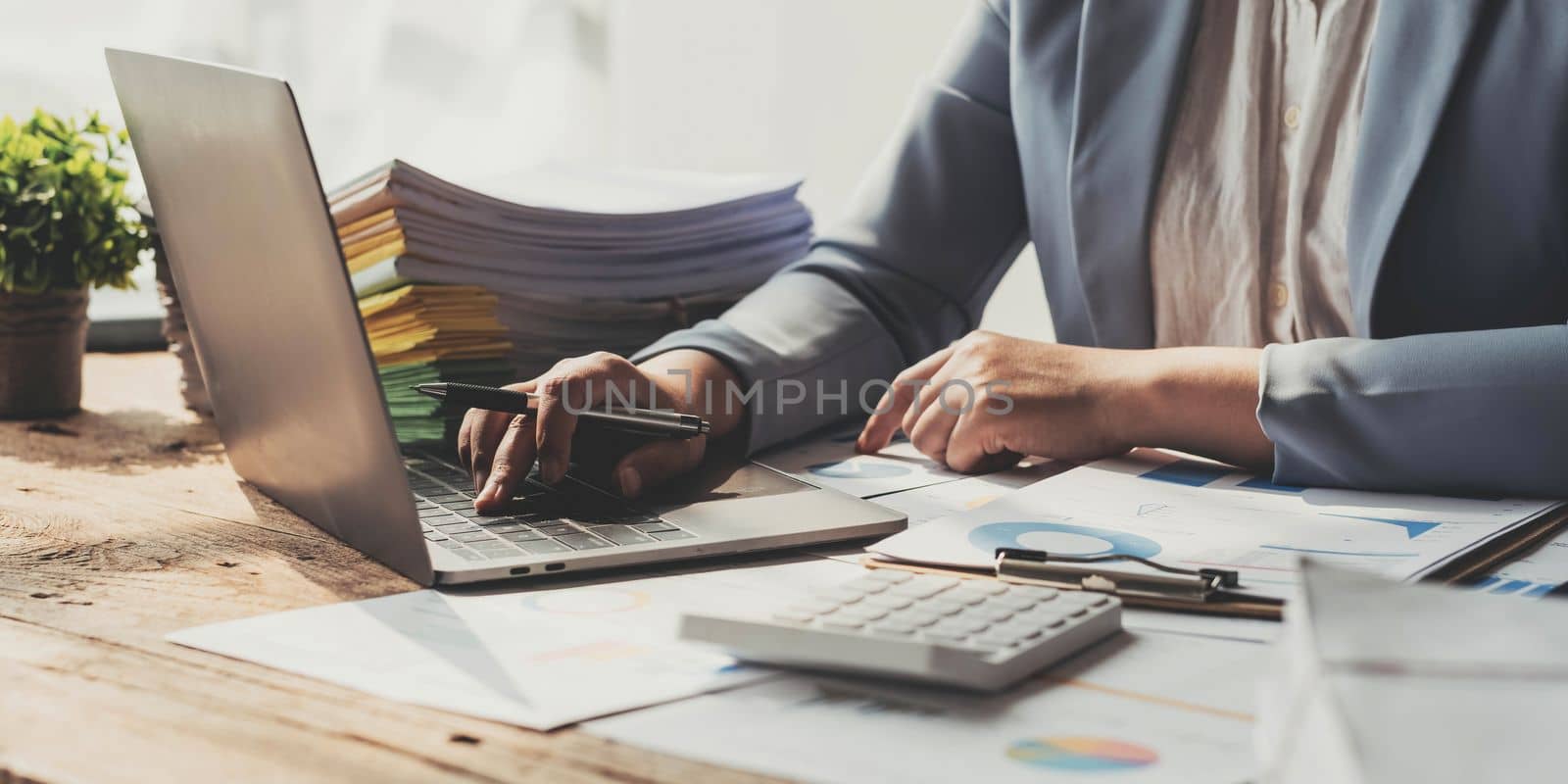Annual, summary report, laptop and paper placed at office desk. Person back view of Asian woman work online and plan financial data with laptop, work from home. Business woman and planner concept by wichayada