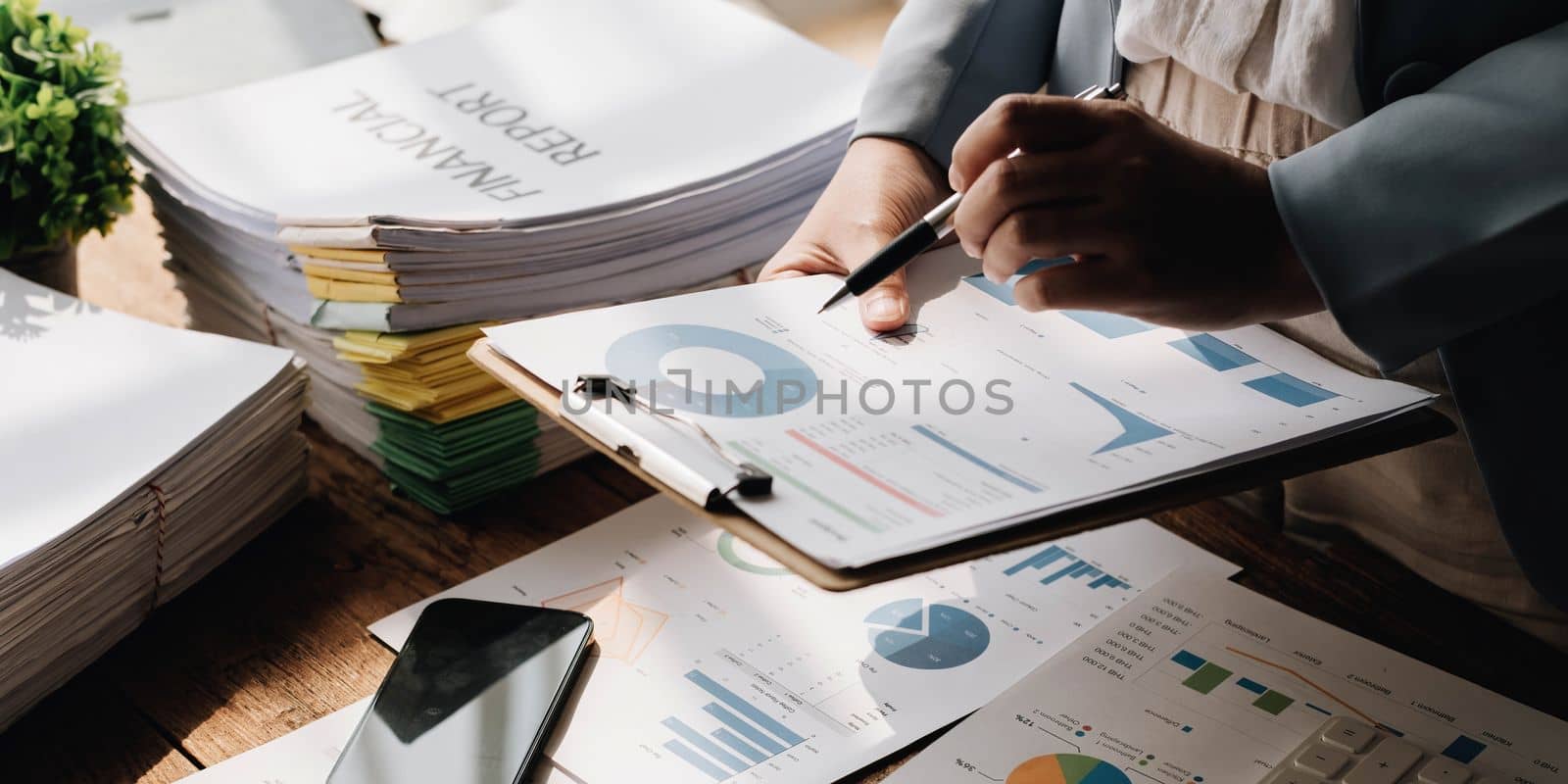 Annual, summary report, laptop and paper placed at office desk. Person back view of Asian woman work online and plan financial data with laptop, work from home. Business woman and planner concept..