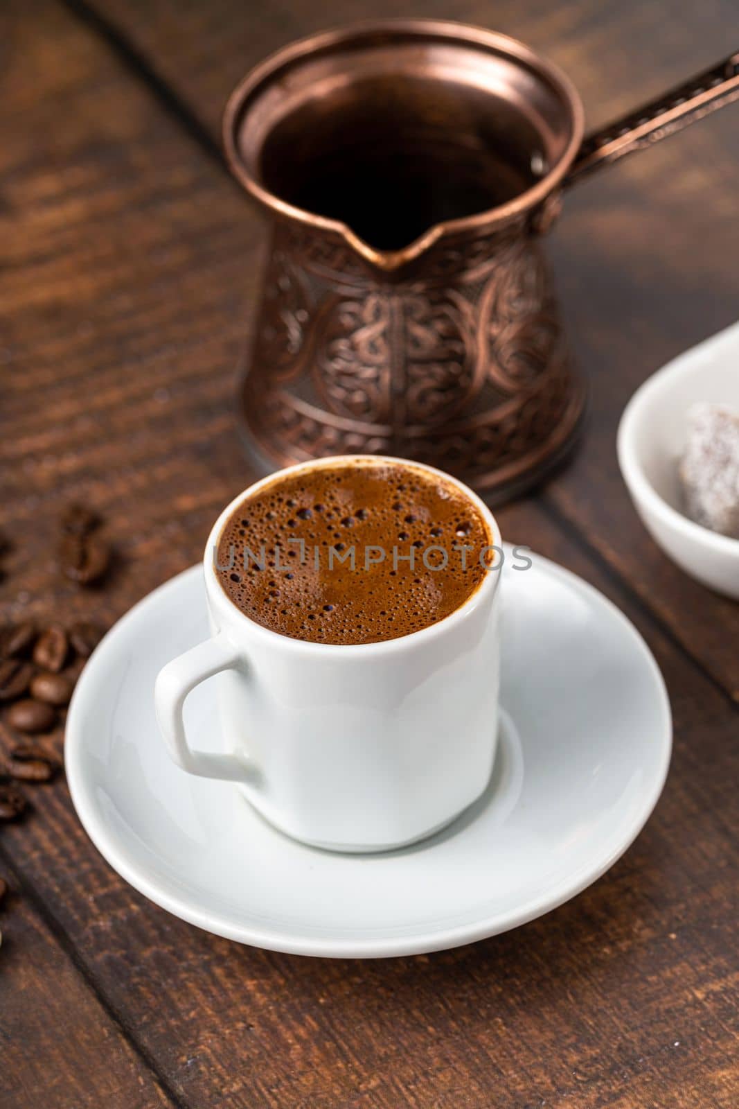 Turkish coffee in classic coffee cup with water and Turkish delight on wooden table