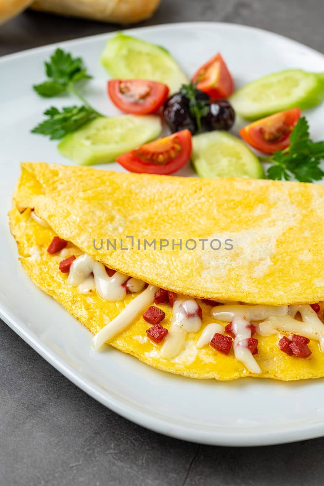 Omelet with feta cheese and Turkish sausage on a white porcelain plate by Sonat