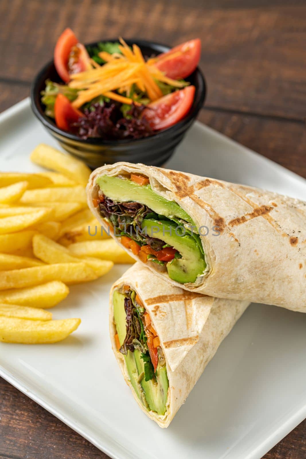 Vegetarian wrap french fries with vegetables on a white porcelain plate by Sonat