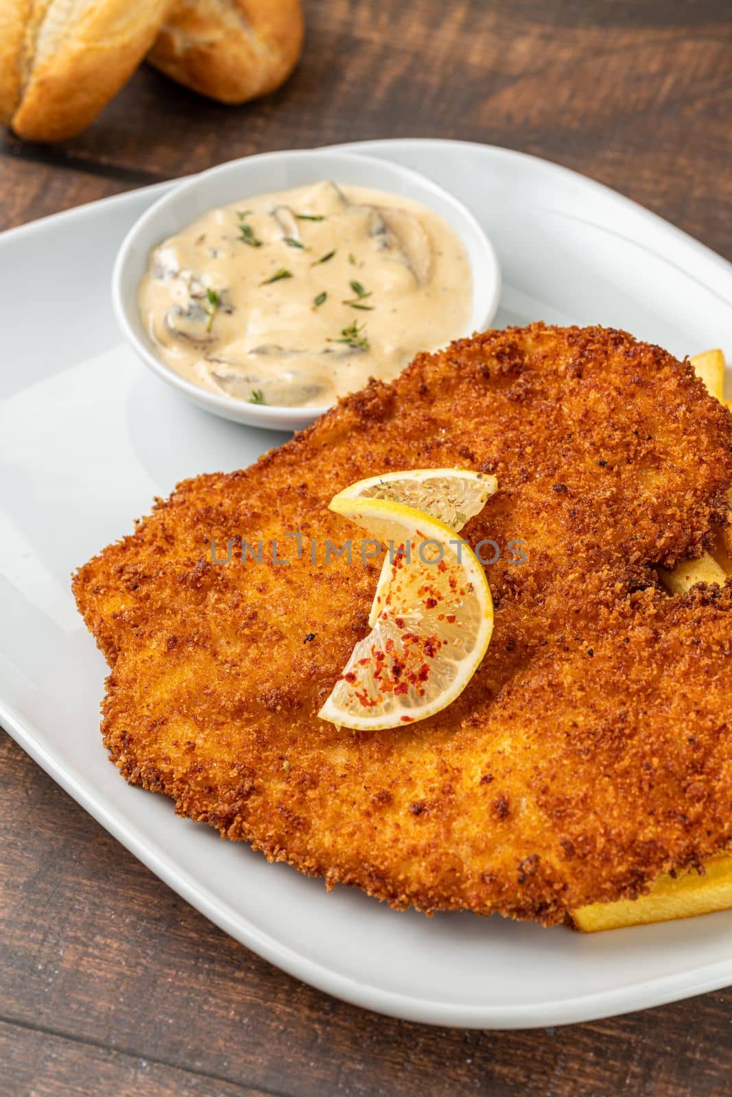 Chicken schnitzel with butter and potato salad on white porcelain plate