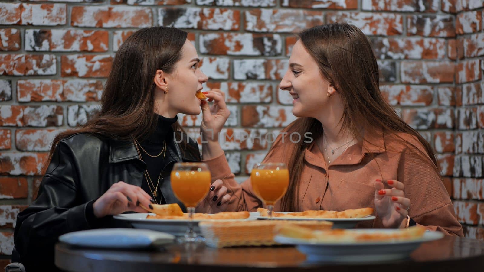 Young girls eat in a cafe and feed each other. by DovidPro
