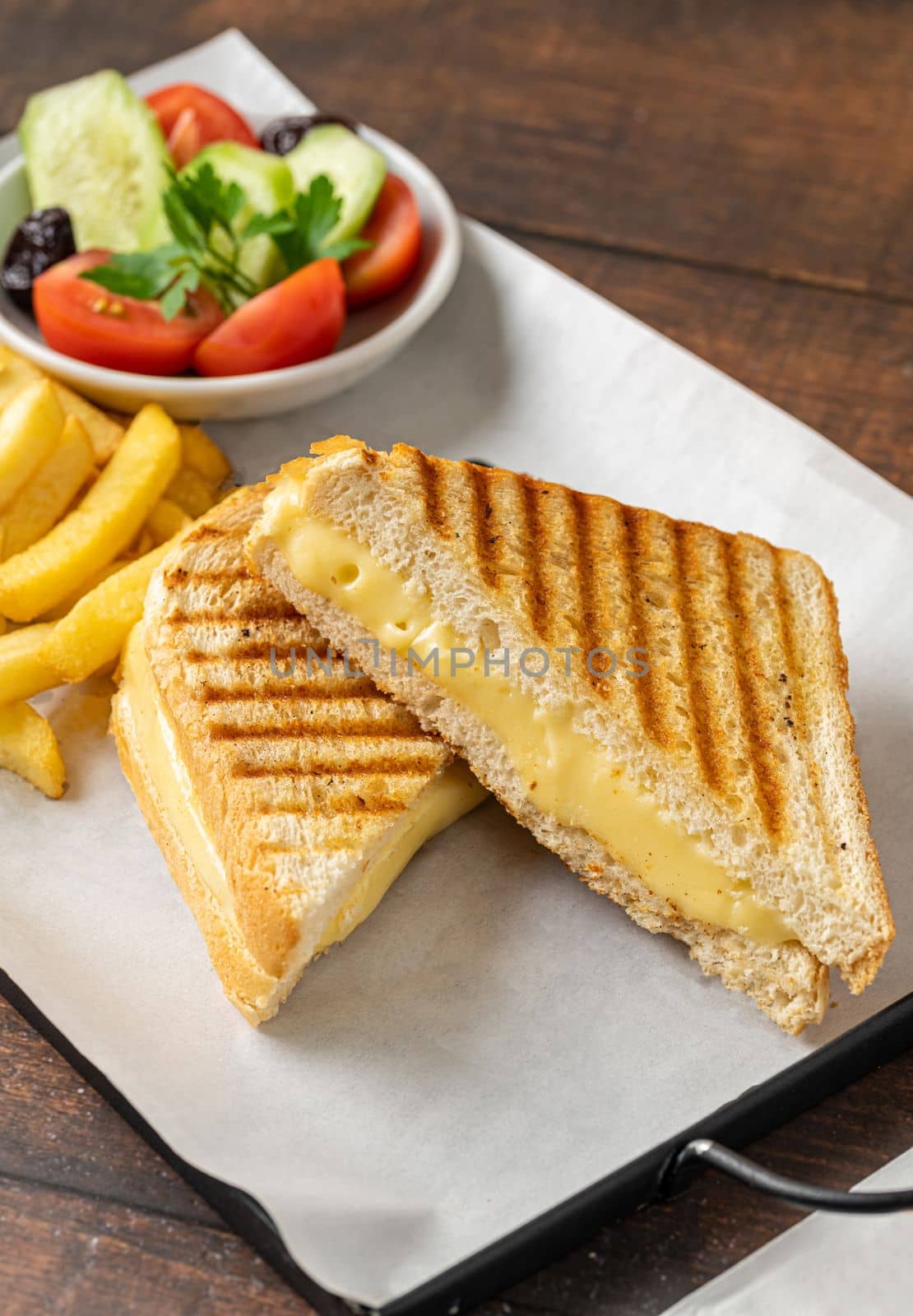 Cheddar cheese toast with french fries and salad on wooden table