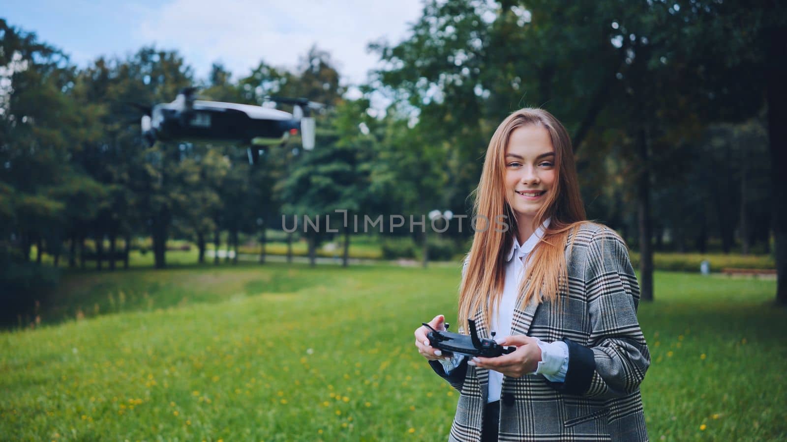 A cute girl controls a drone in the park