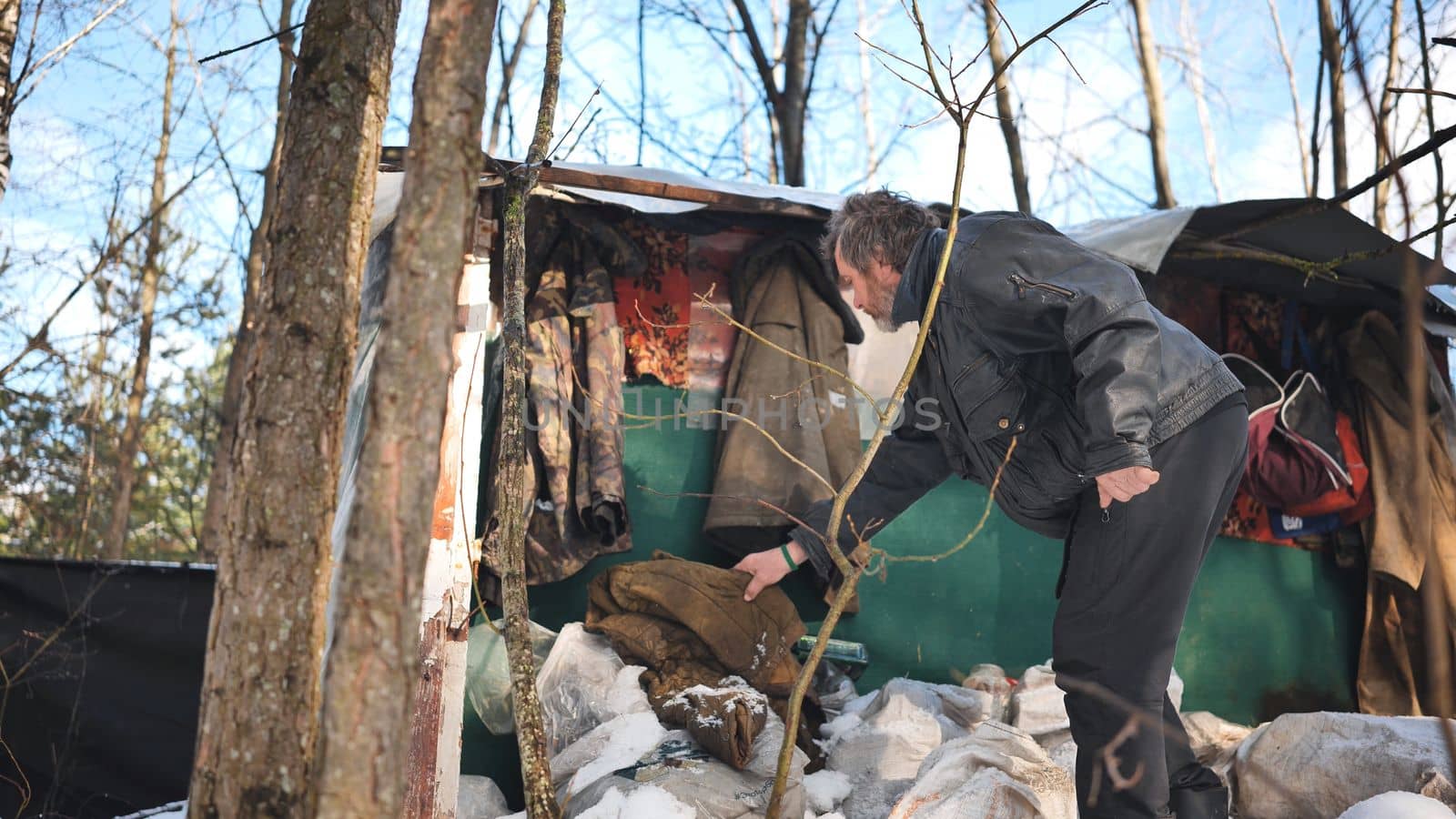 A homeless man goes through things at his cabin in the woods in winter