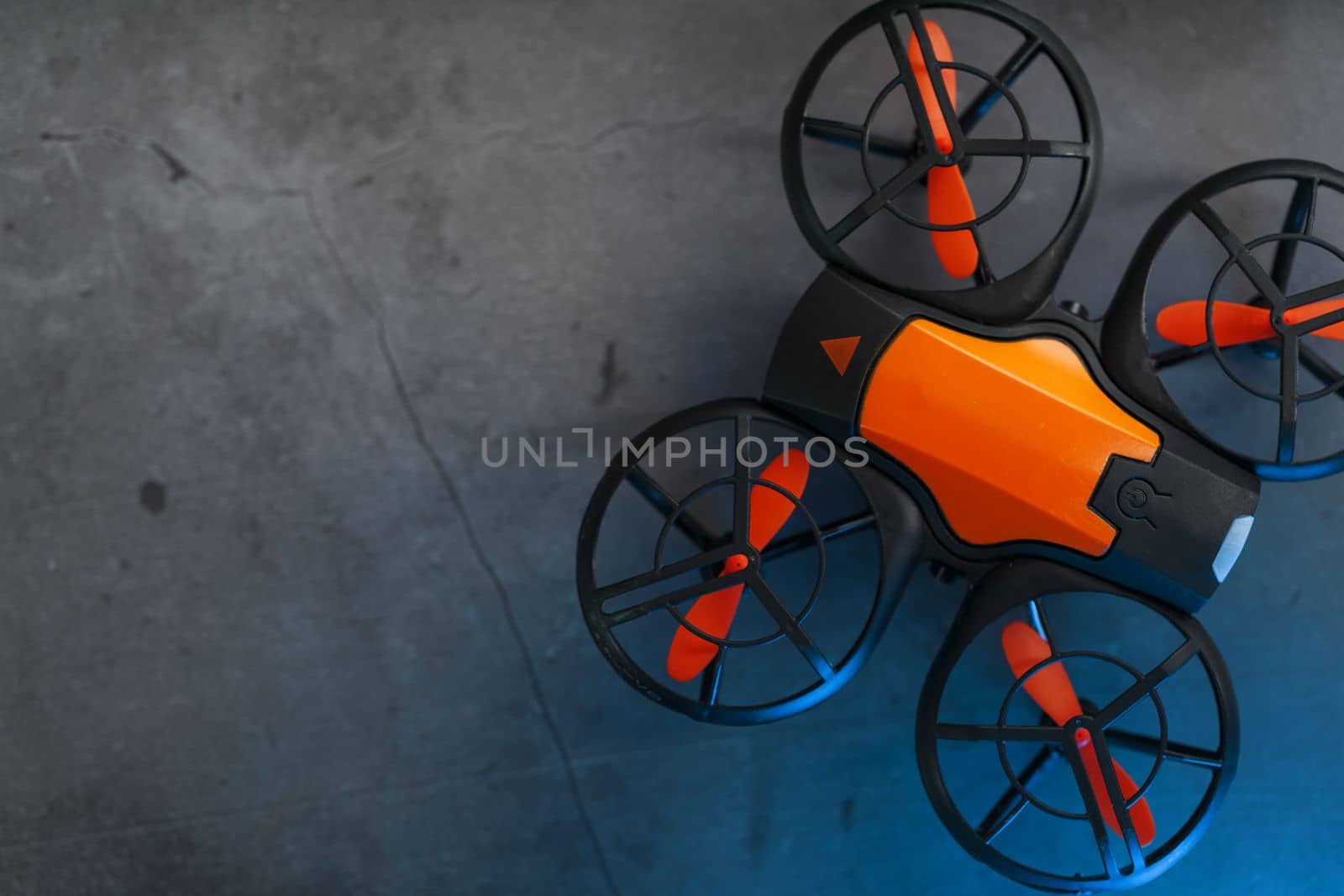 Orange quadcopter mini spy drone on a dark background with blue backlight and free space