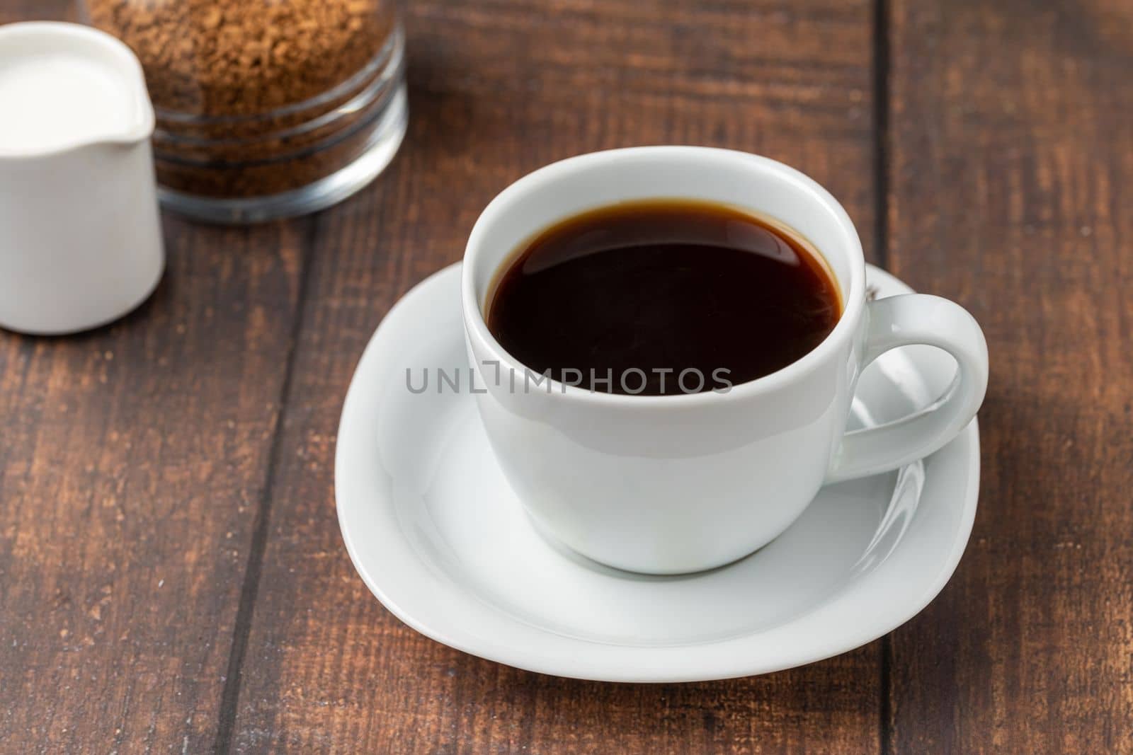 Instant or granulated coffee in white cup on wooden table