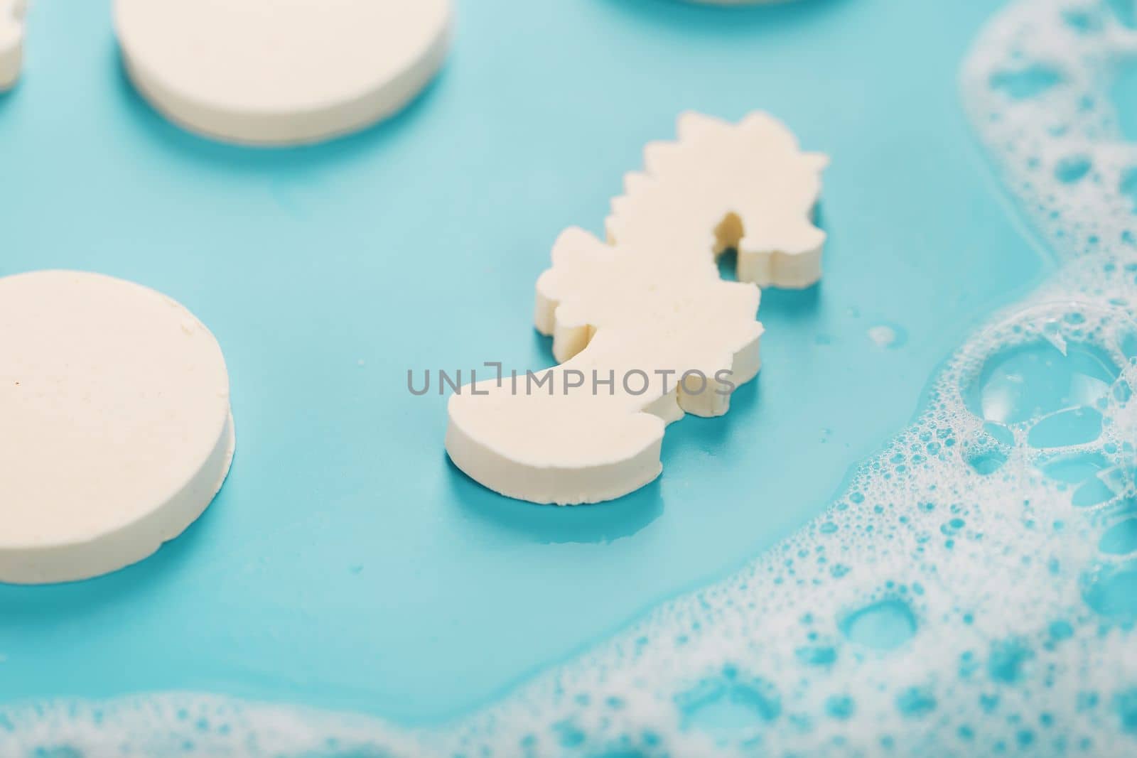 Soap in the shape of a seahorse and circles with foam on a blue background