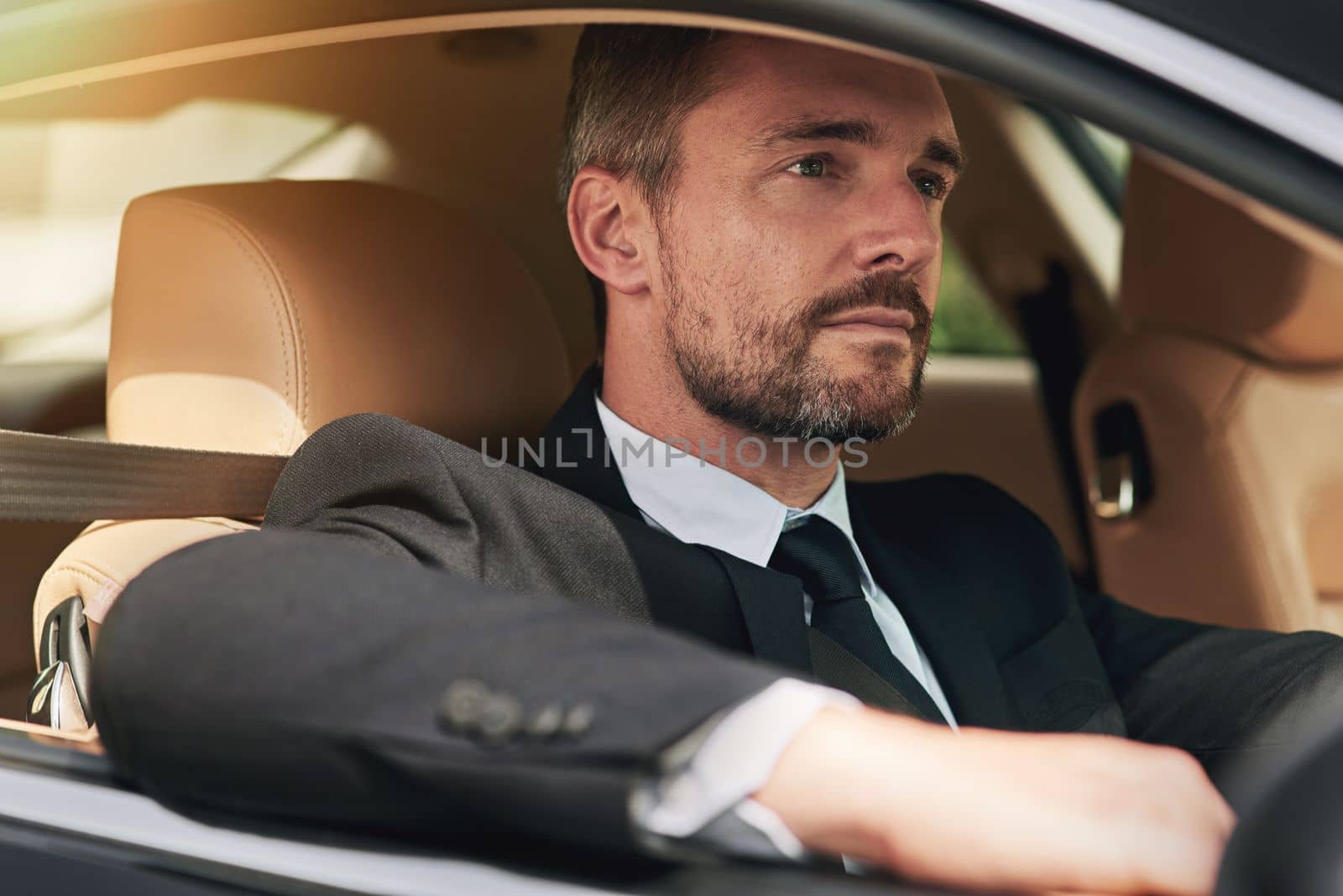 Driving himself to work. a handsome businessman on his morning commute to work