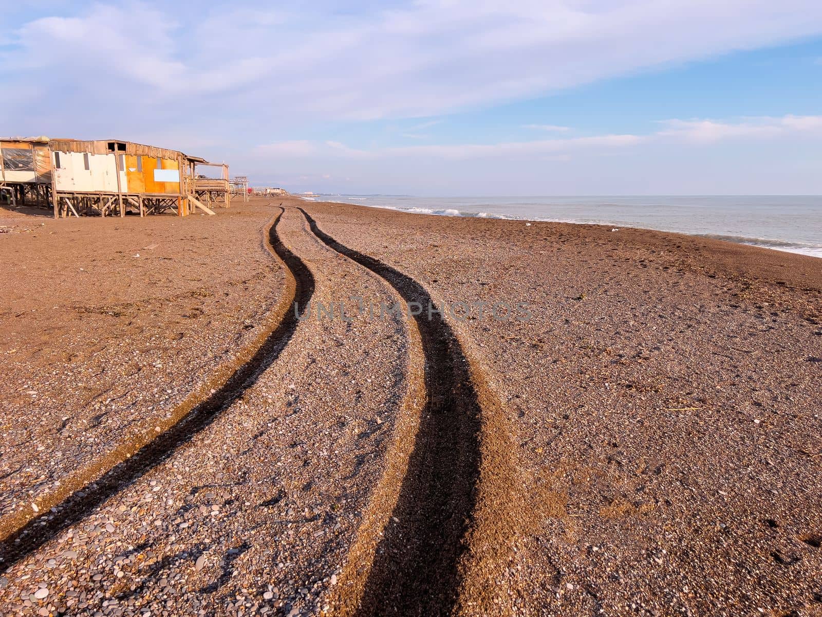 Wheel track of a 4x4 vehicle driving past the beach at sunset by Sonat