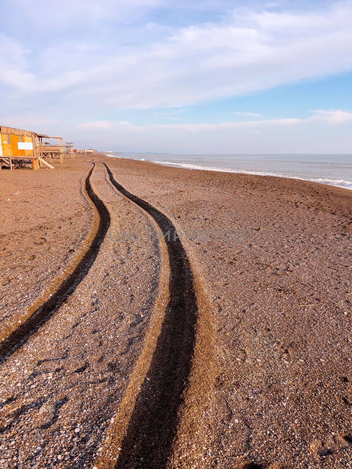 Wheel track of a 4x4 vehicle driving past the beach at sunset by Sonat