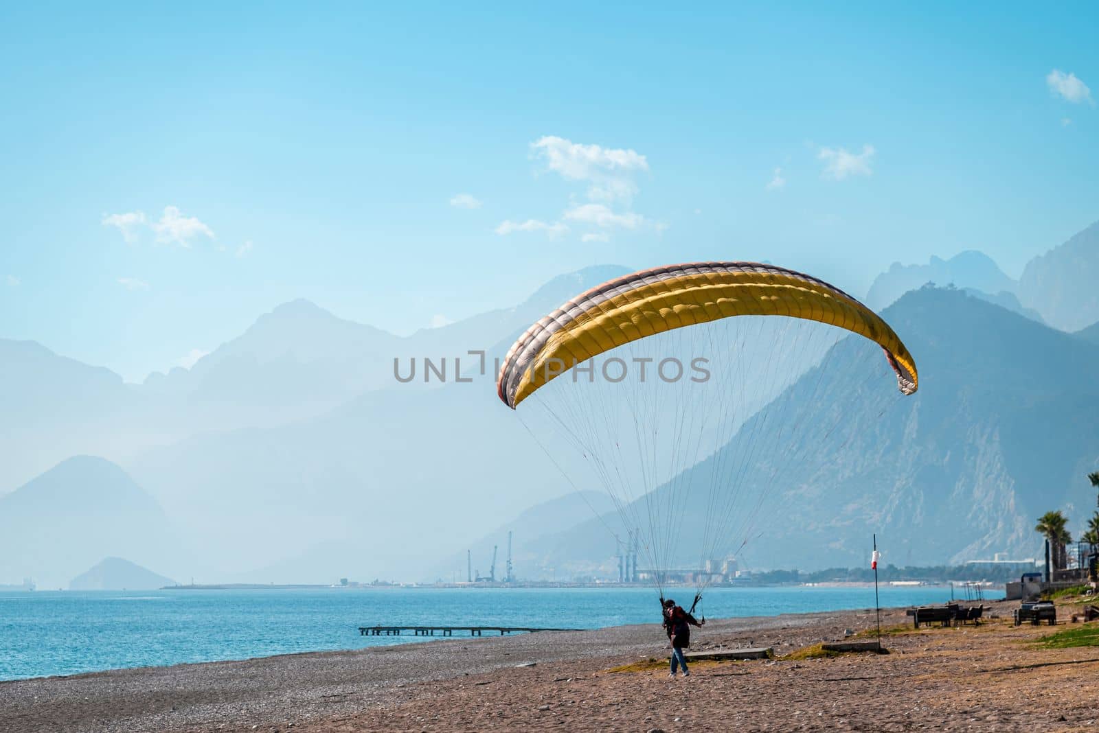 Man practicing paragliding on a windy day on the beach by the sea by Sonat