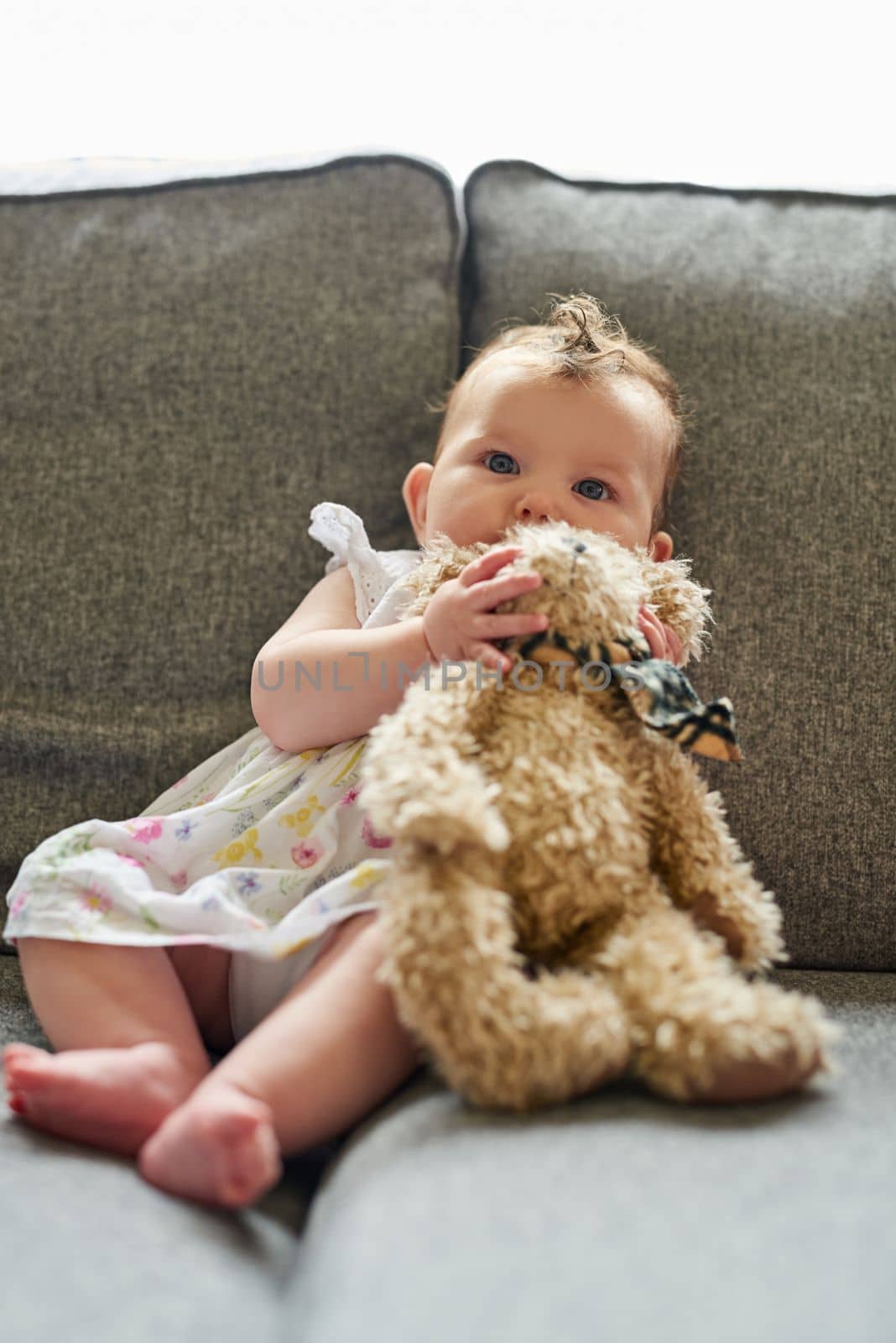 Its her favourite teddy. Portrait of an adorable baby girl playing with a teddybear at home. by YuriArcurs