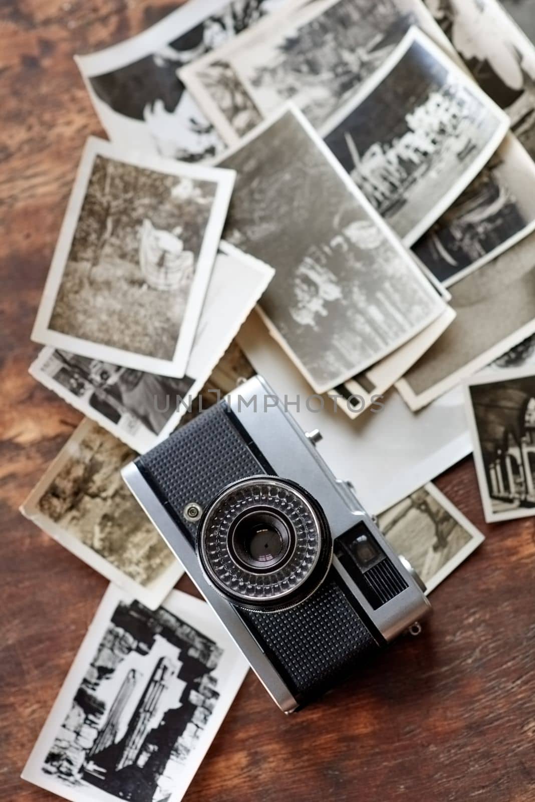 Snapshots from the past. An old-fashioned camera lying on top of a pile of black and white photographs. by YuriArcurs